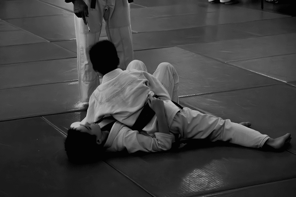 Black and white photo of a student practicing a submission with a yellow belt