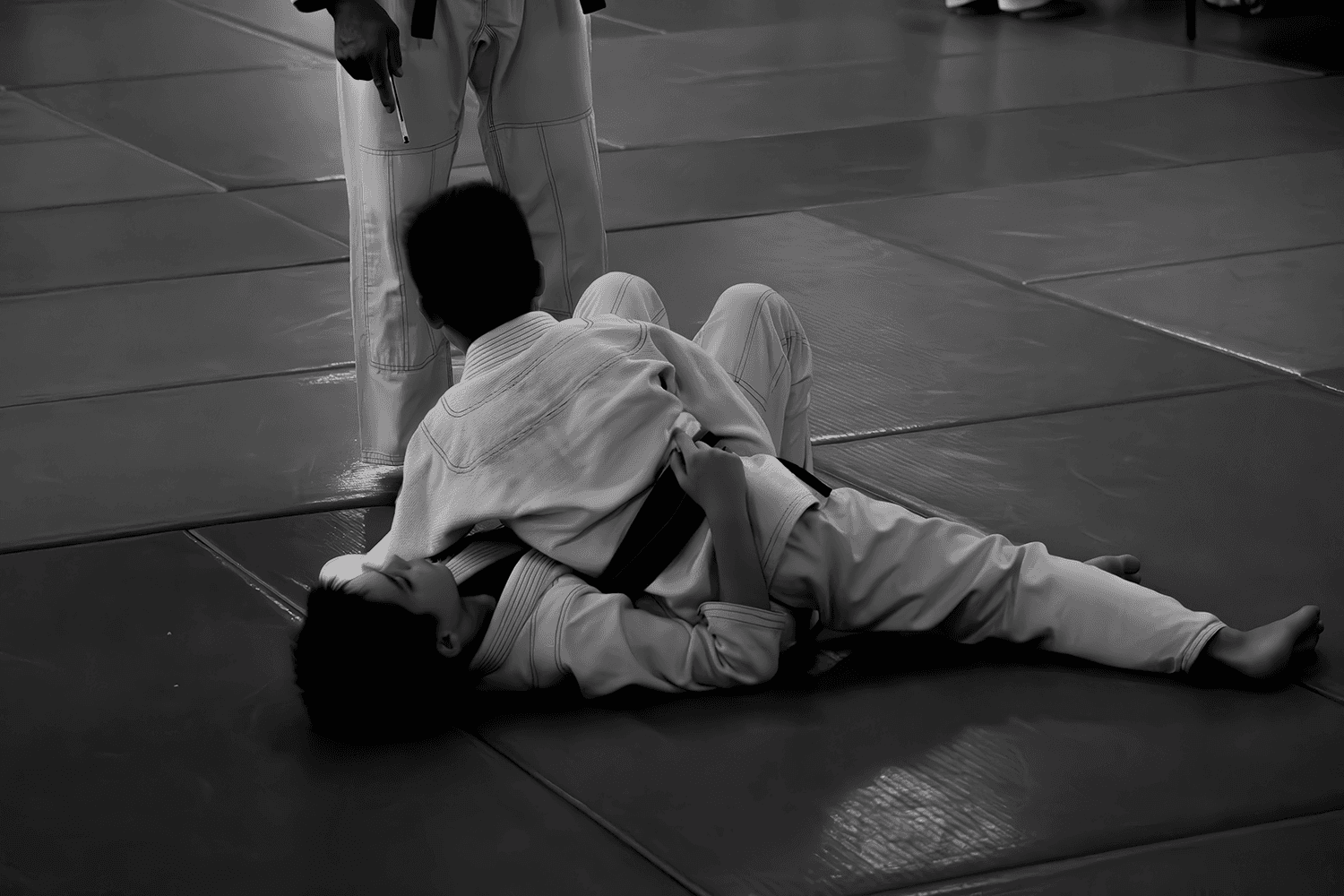 Black and white photo of a student practicing a submission with a yellow belt