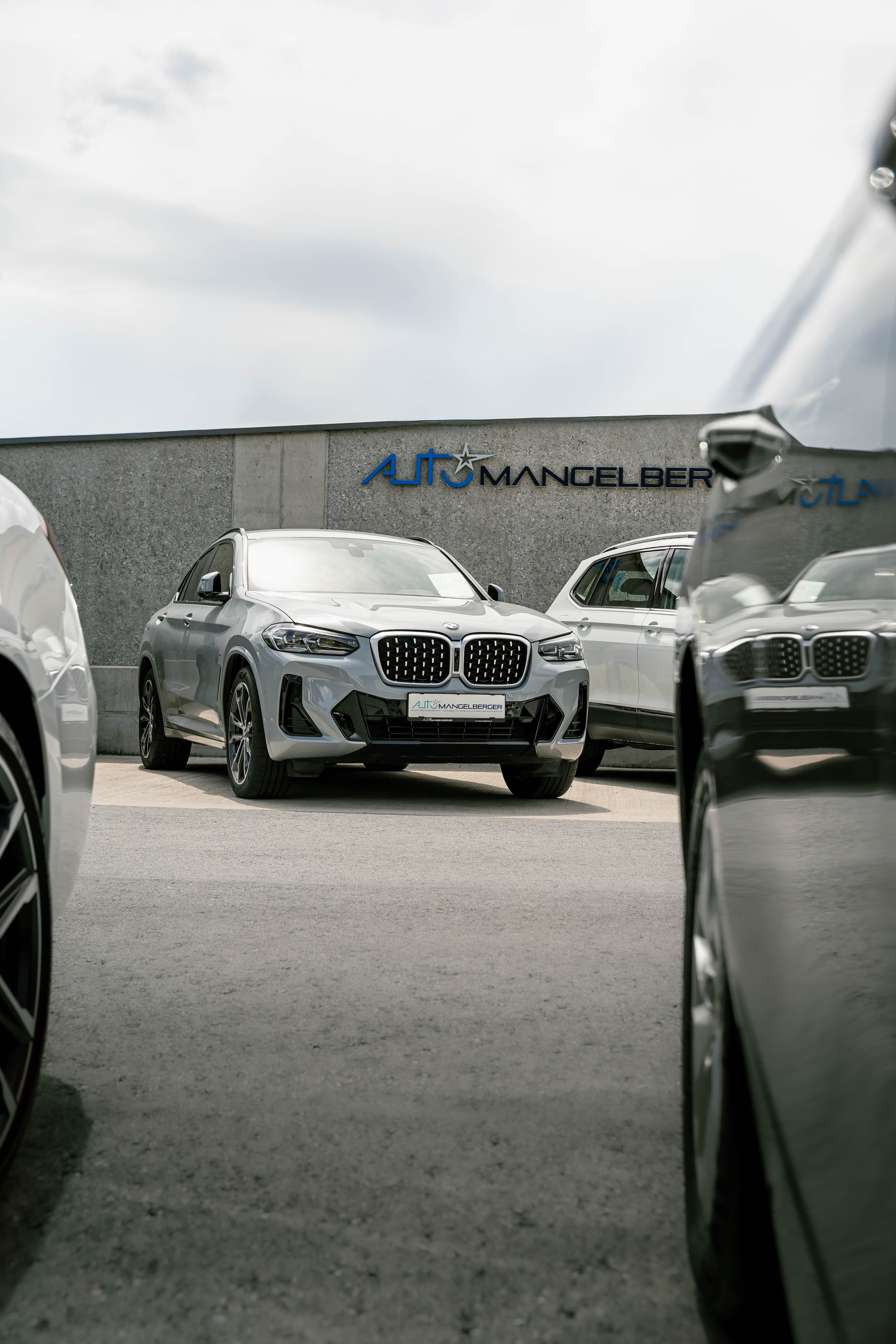 BMW X4 M Competition in grau auf Parkplatz vor Autohaus