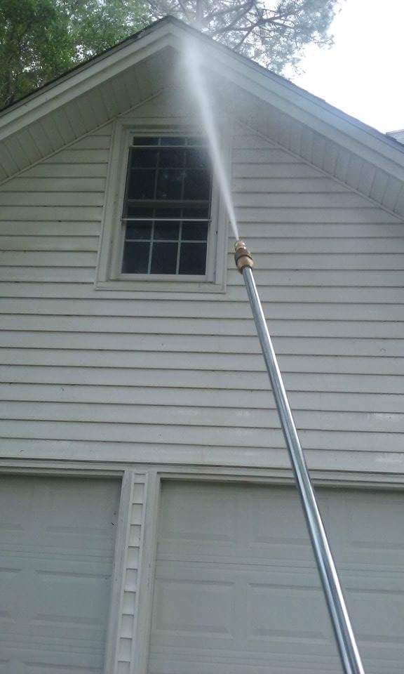 Technician soft washing vinyl siding in Kent OH using low‑pressure cleaning to remove algae.