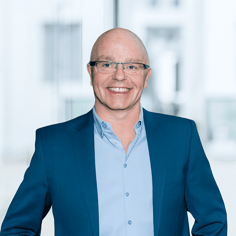 Bli mann i blå skjorte med mørkeblå blazer mot lys bakgrunn