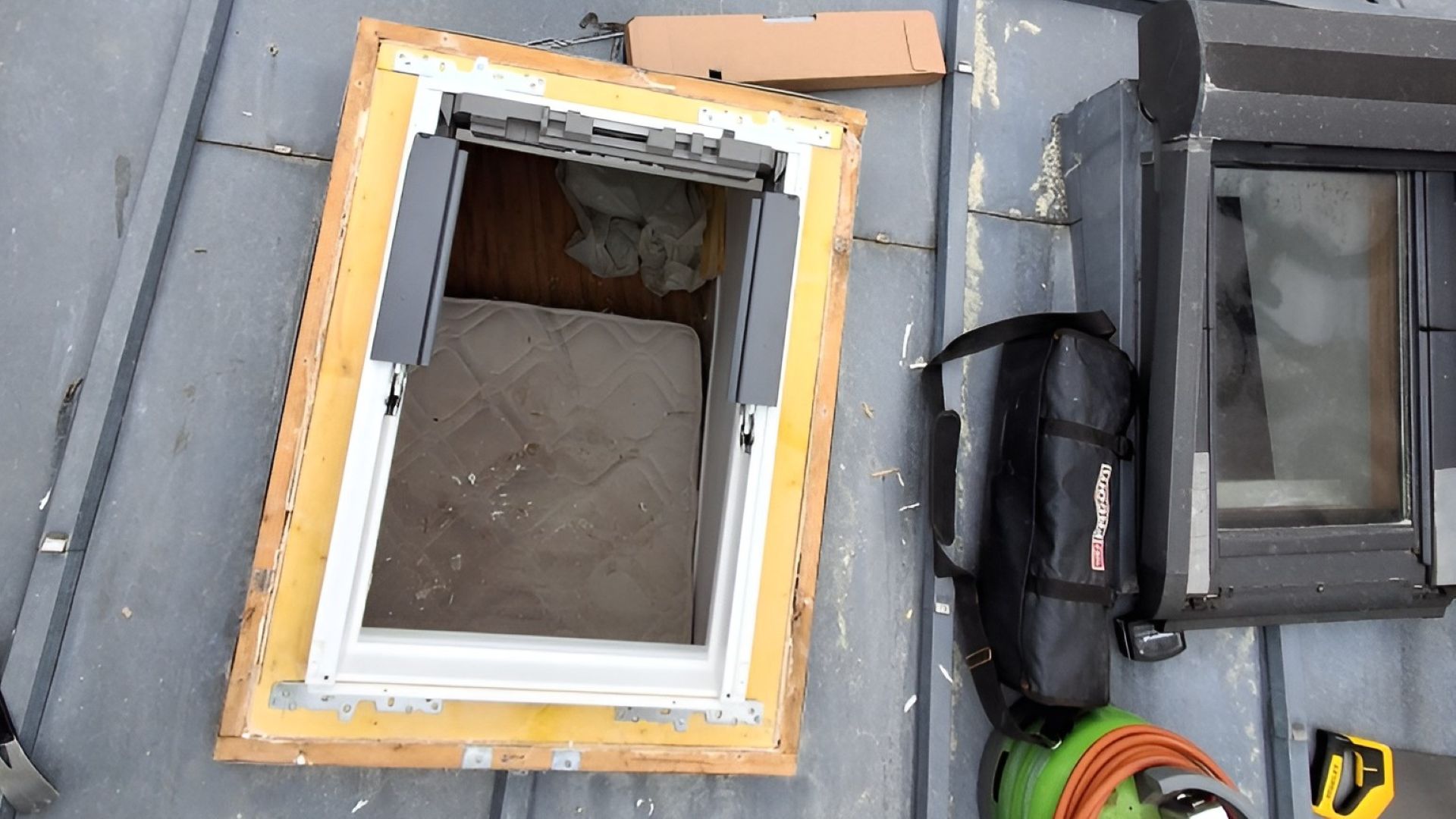 Installation d’une fenêtre de toit Velux sur toiture en ardoise avec cadre d’étanchéité et ouverture prête à poser.