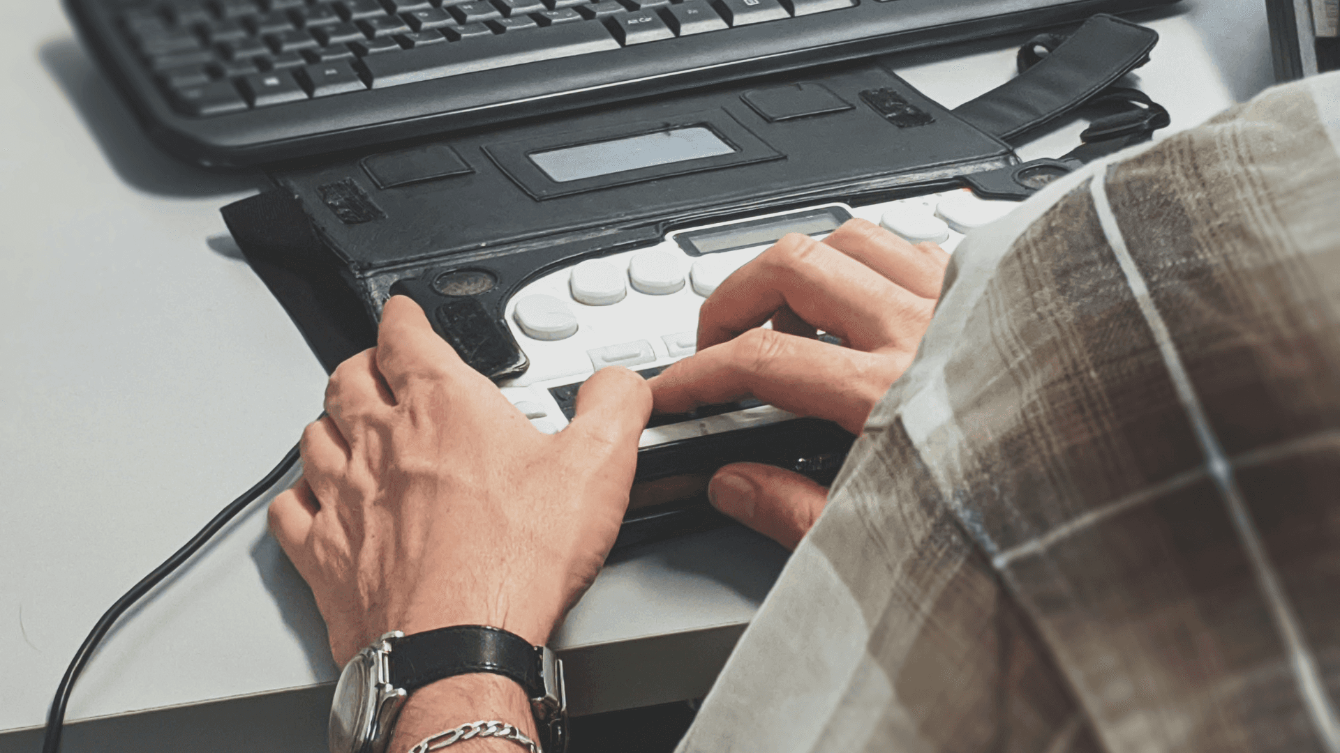 A close up shot of a person using an assistive keyboard to access their laptop