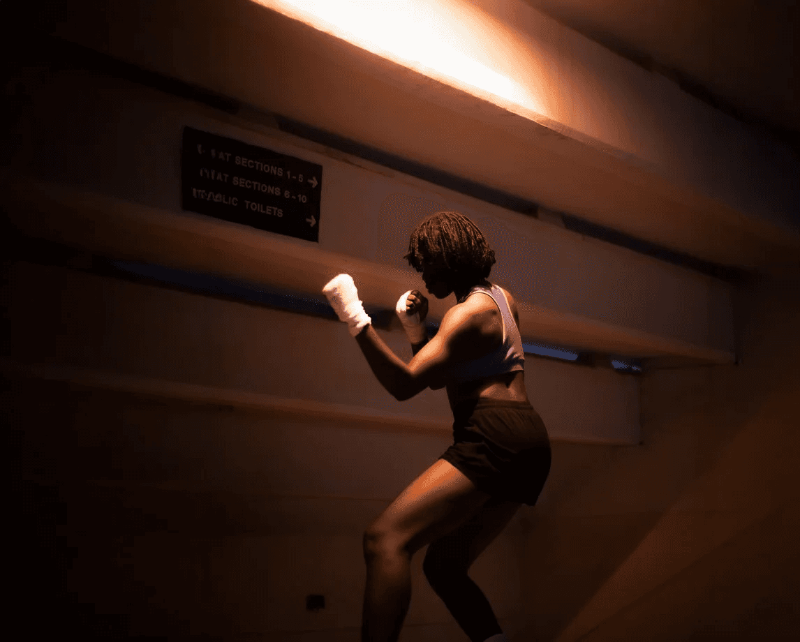 Woman stretching with arms overhead in a gym.