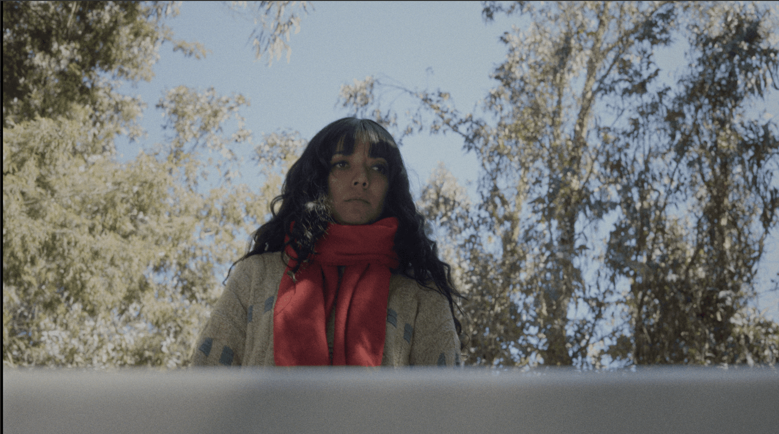 Woman in a light suit sitting thoughtfully against a terracotta wall