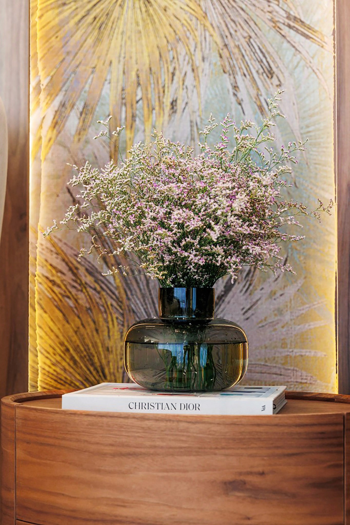 Villa Trio interior styling detail with glass vase, pink florals, and a Christian Dior book
