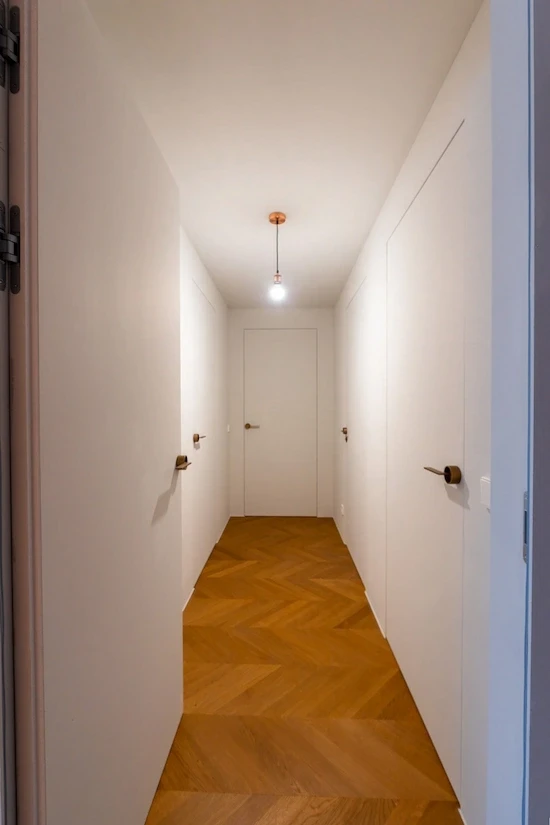 Heller Flur mit frisch verlegtem Chevron-Parkettboden in warmem Holzton