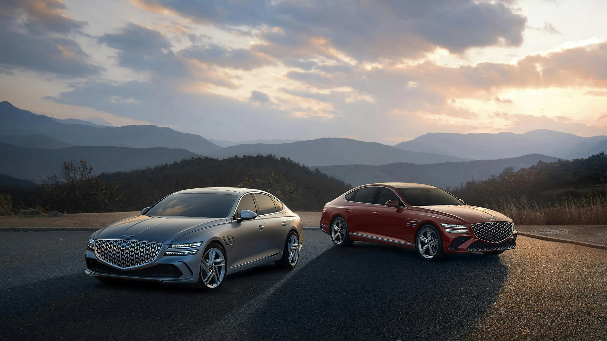 Two premium sedans parked on mountain road at sunset, luxury automotive photography
