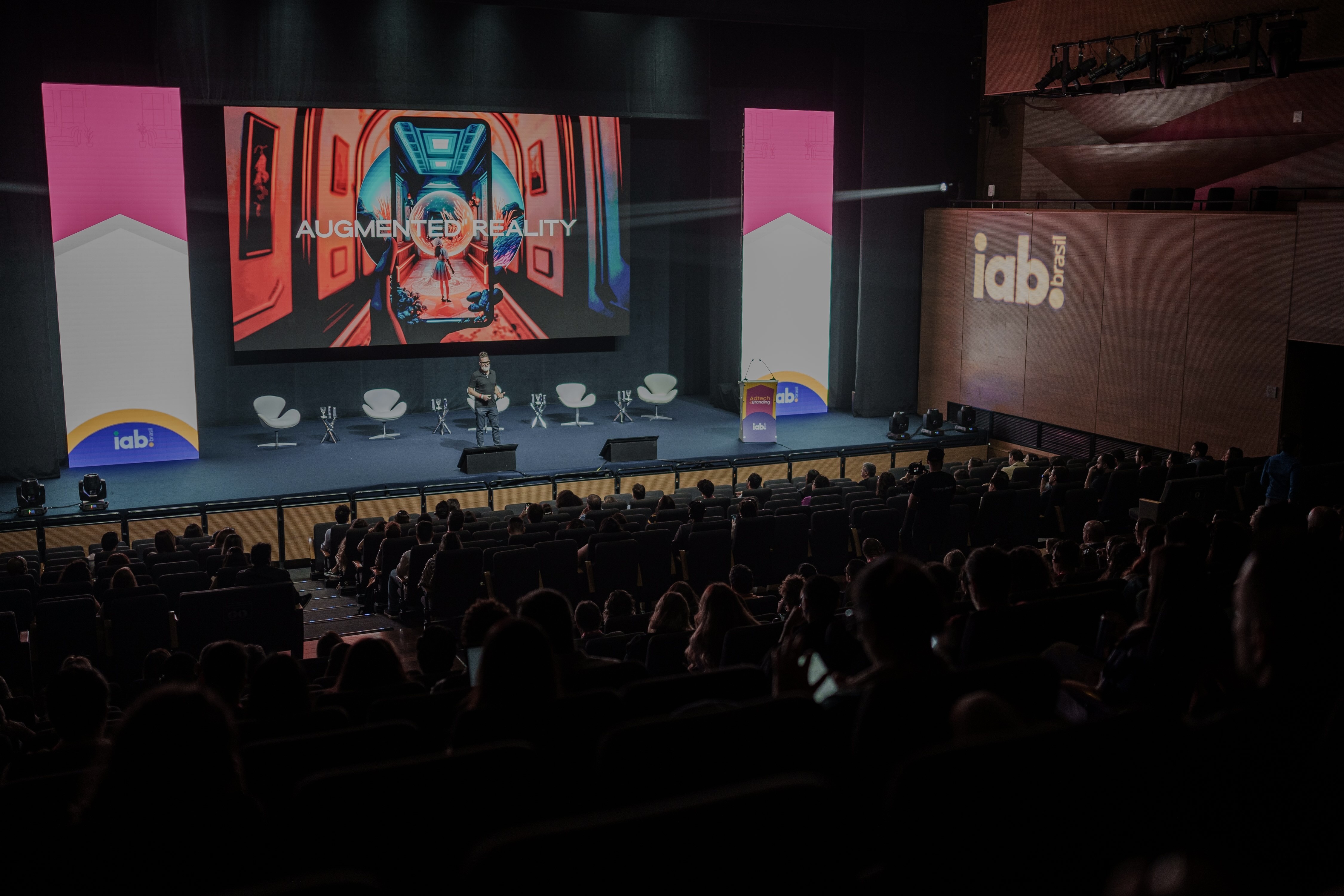 Image of large auditorium with Neil speaking