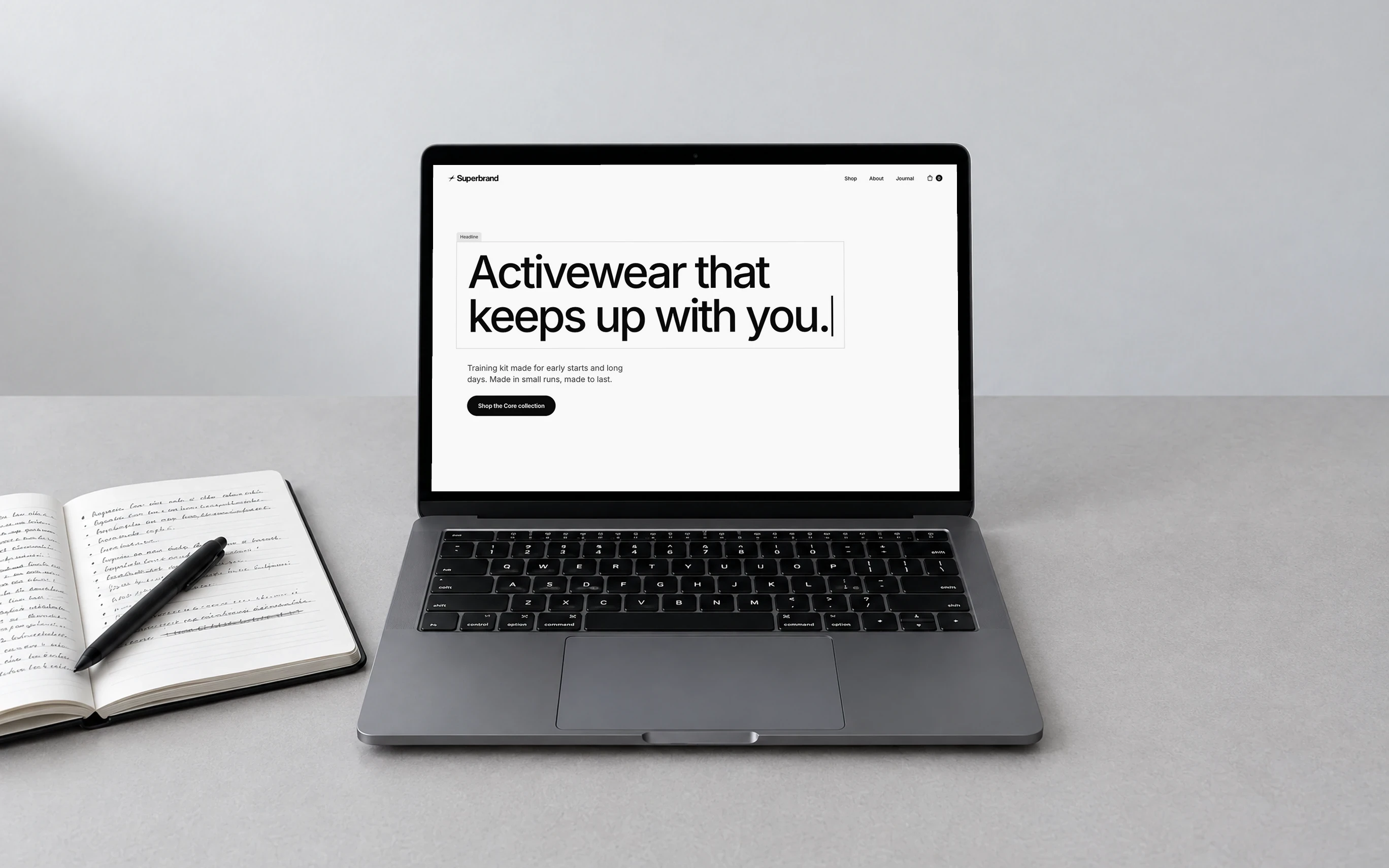 A laptop showing Superbrand’s homepage line, “Activewear that keeps up with you.”, beside an open notebook and pen.