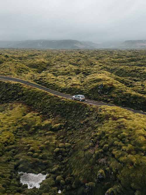 Car on winding road in lush landscape, captured for a landcover ad.