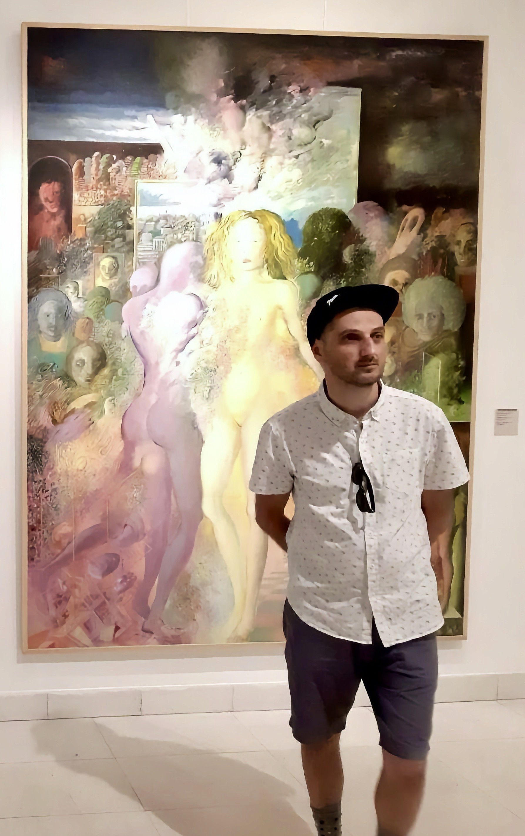 Boris Jov, freelance UX/UI designer, standing in front of large figurative paintings at an art gallery