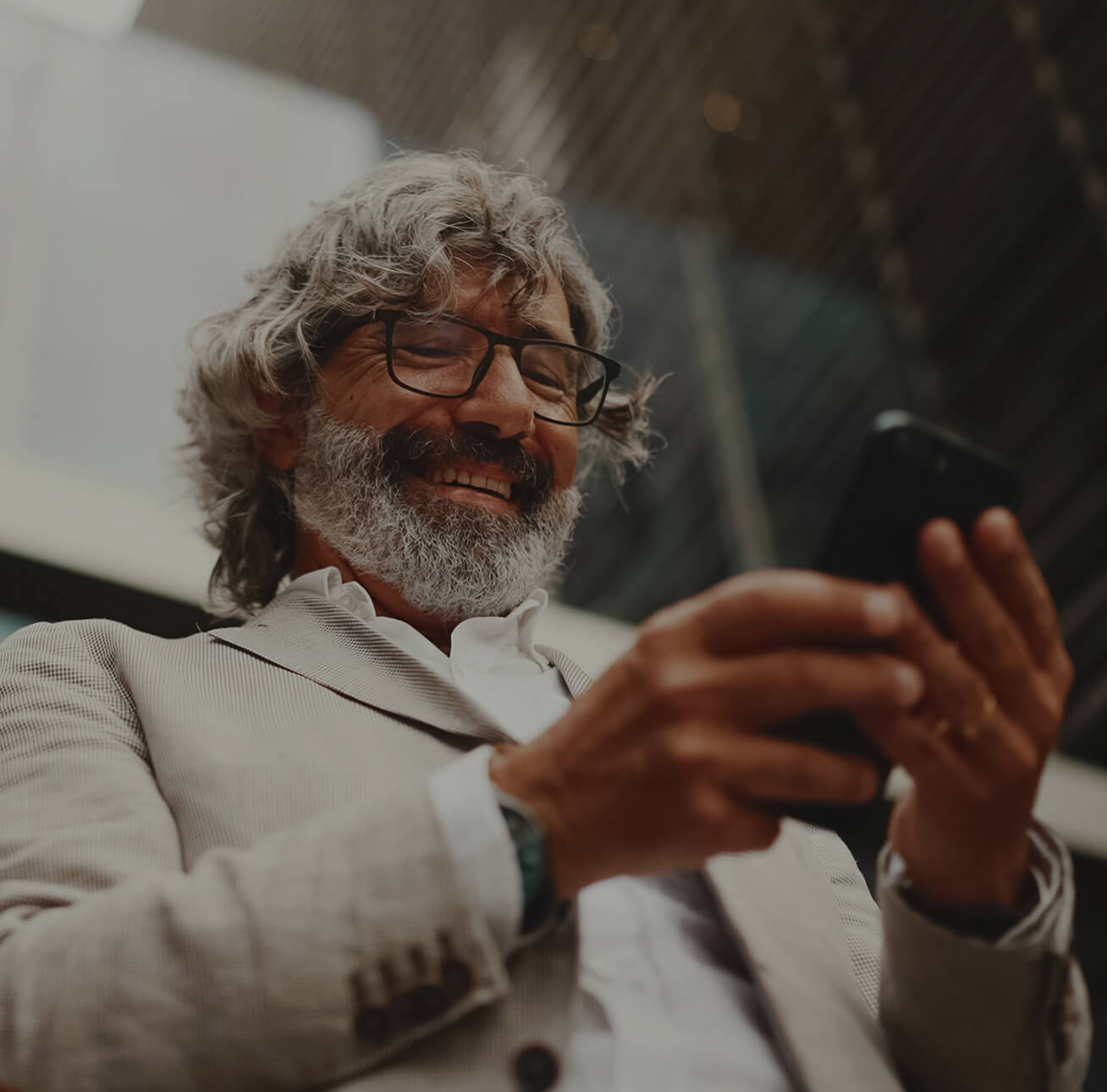 A smiling older man looking down at his phone