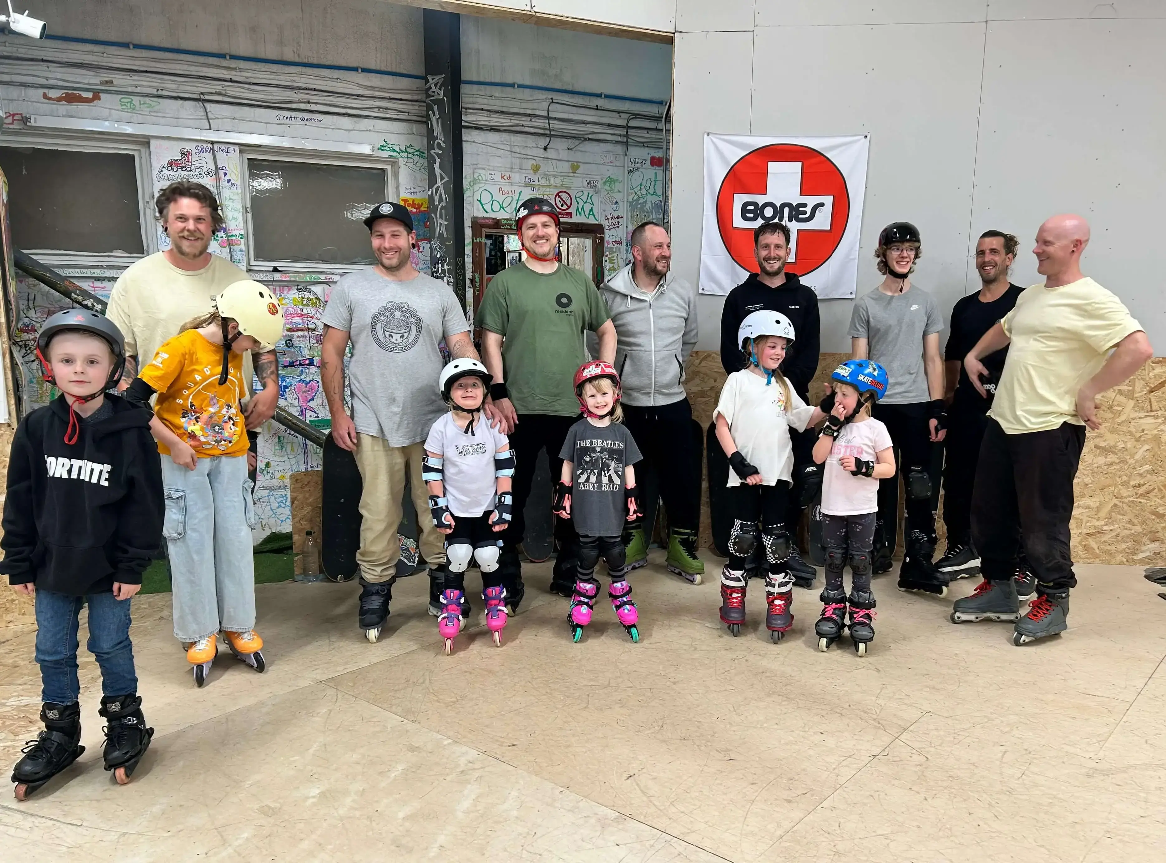 A group of adults and children stands together, smiling, at the Skate Farm