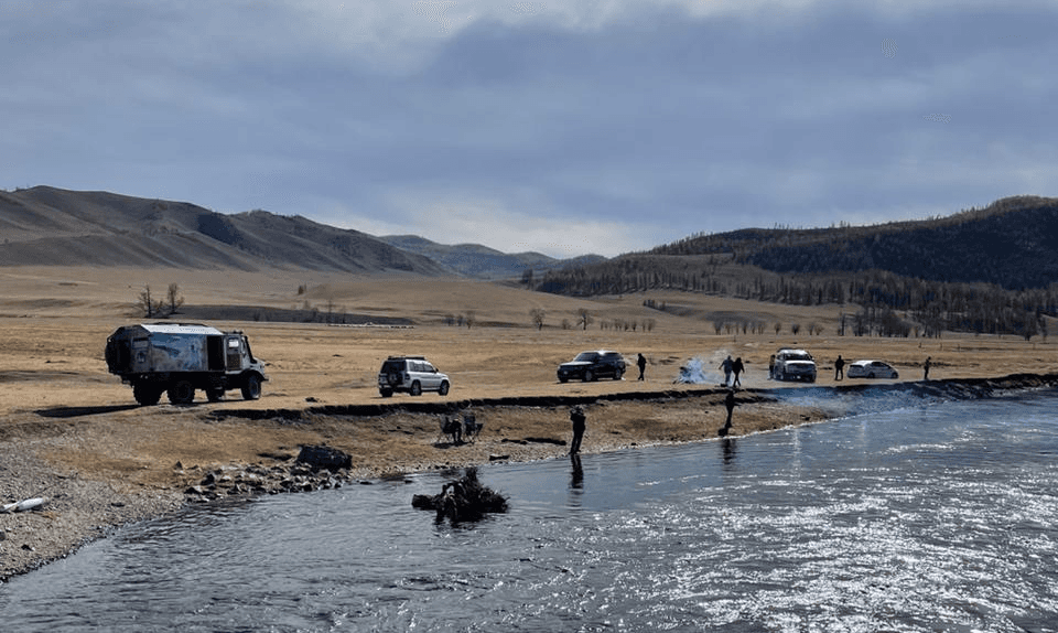 cars in Mongolia with tourists by the river