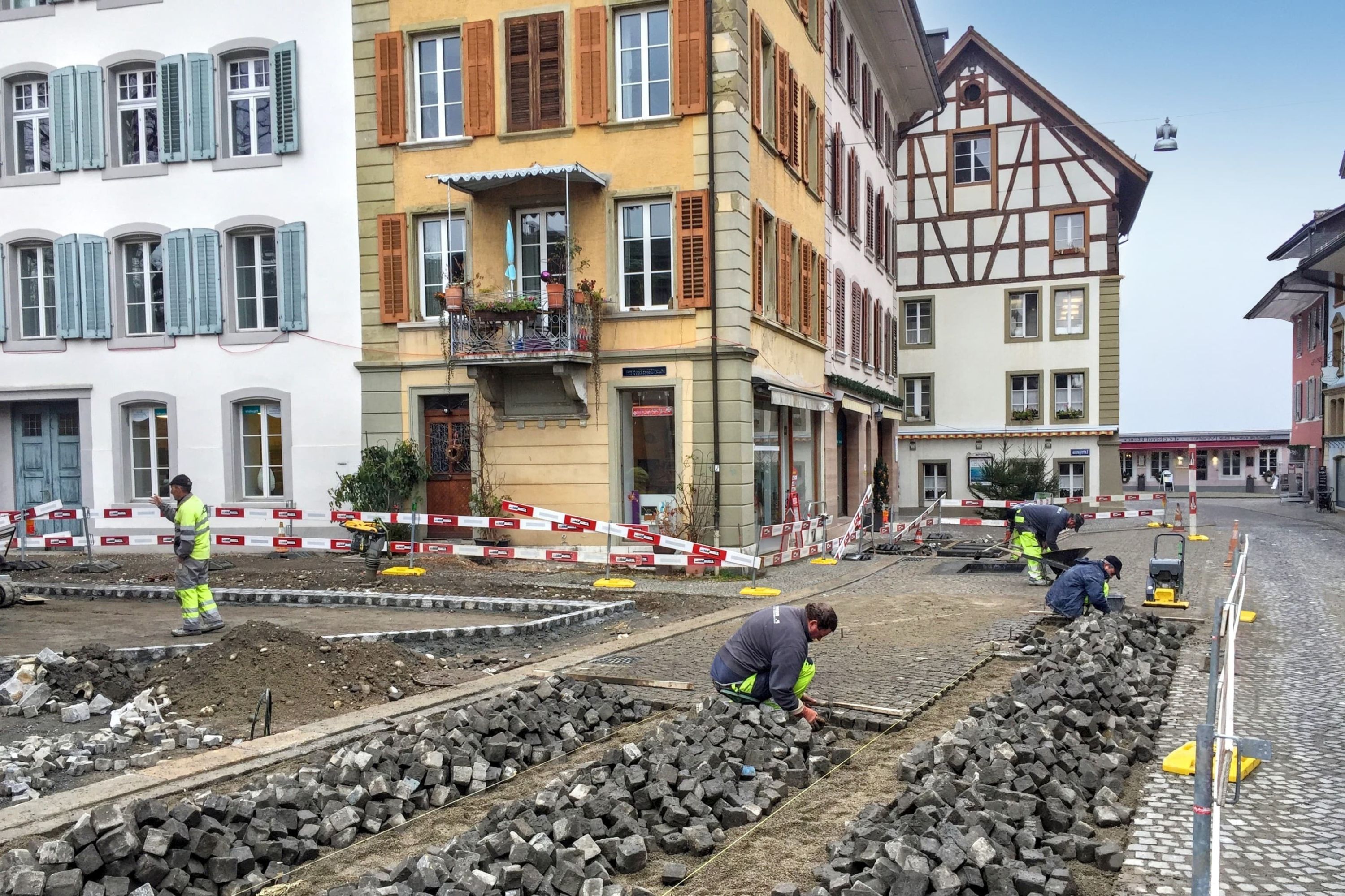 Strub Bau AG team restoring cobblestone pavement in a historic city center – precision stonework and urban infrastructure renovation.