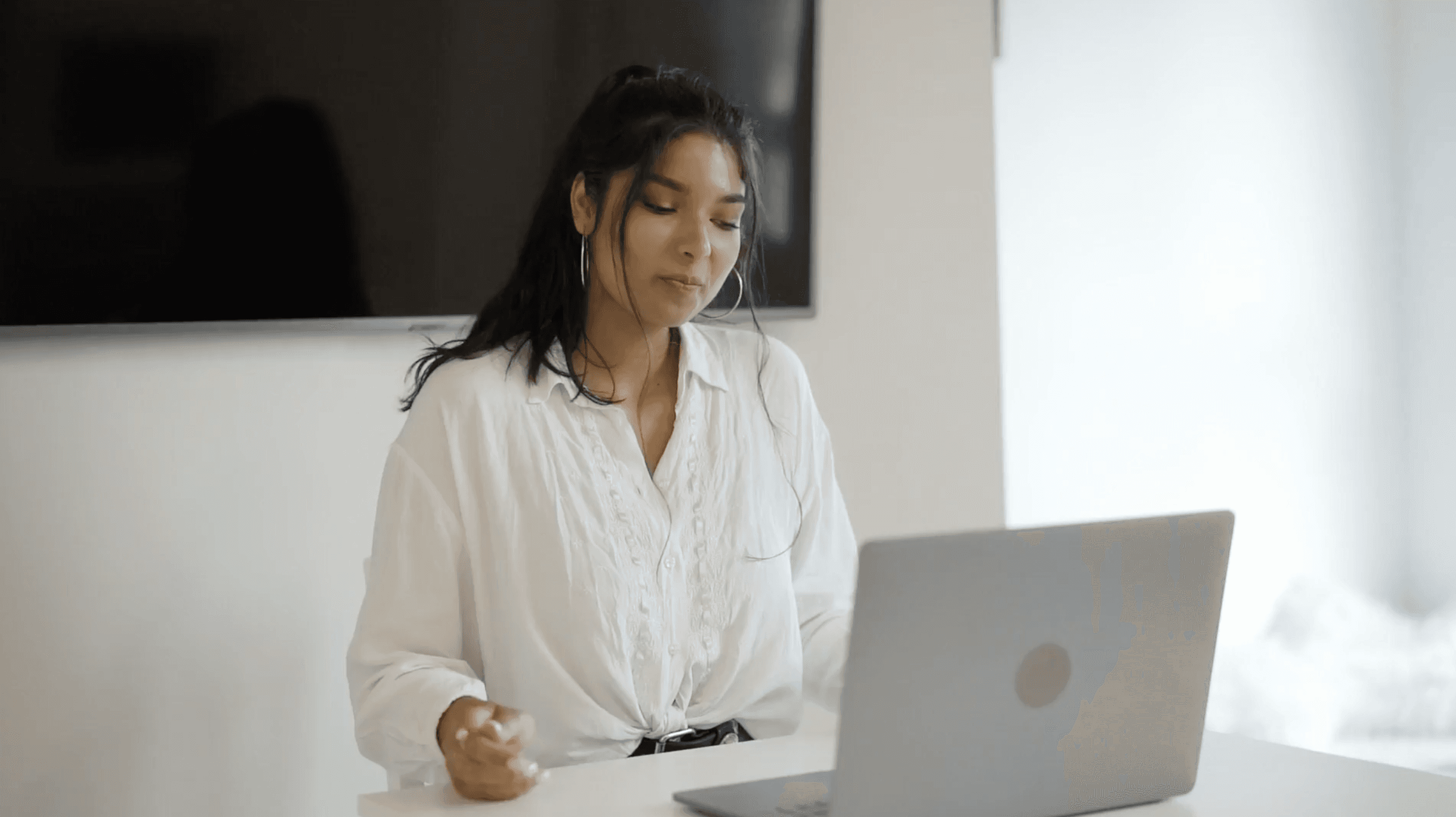 a woman sitting at a desk in front of a laptop
