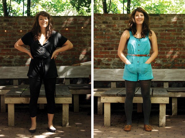 A woman with long brown hair stands in front of two wooden benches. She wears a black sleeveless top, black pants, and black shoes. Her left hand rests on her hip, and her right hand is in her pocket. The bench to her left is longer and has a backrest. The bench to her right is shorter and has no backrest. The background includes a brick wall and trees. Lighting is bright and natural.