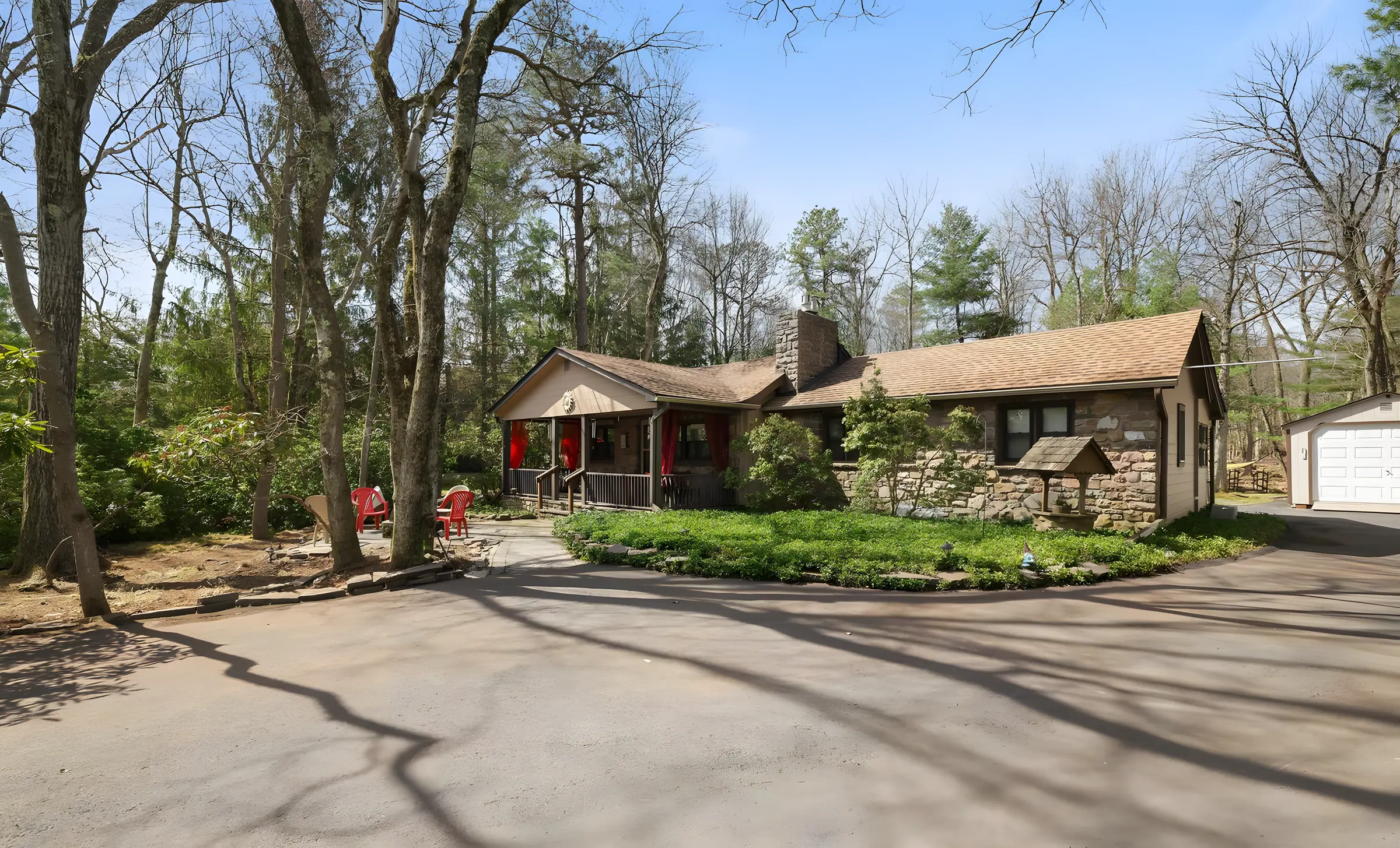 Stone ranch home with large paved driveway among tall trees at Relax in Style, Lake Harmony, PA