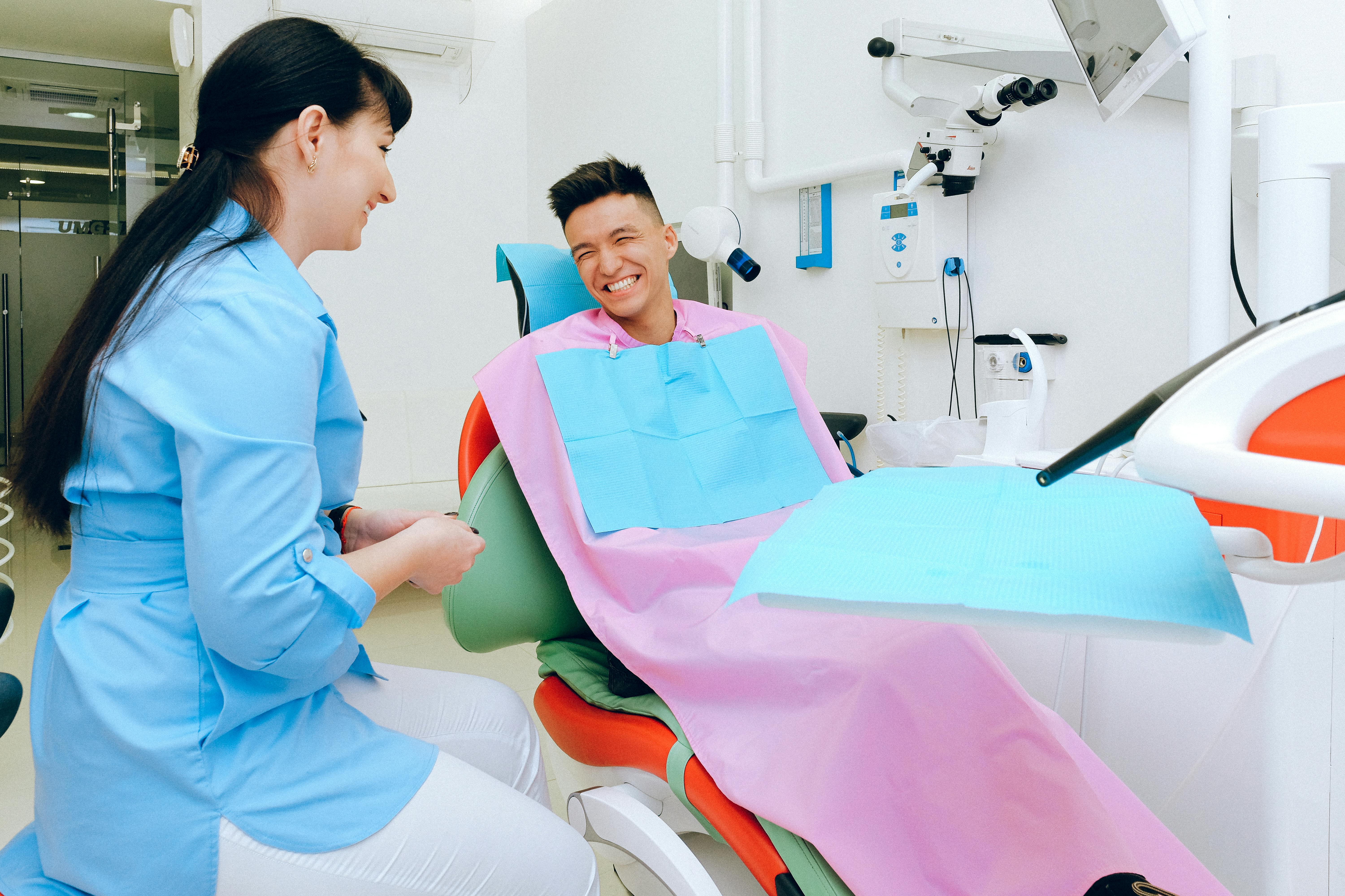 patient sitting in dental chair smiling at dental hygienist