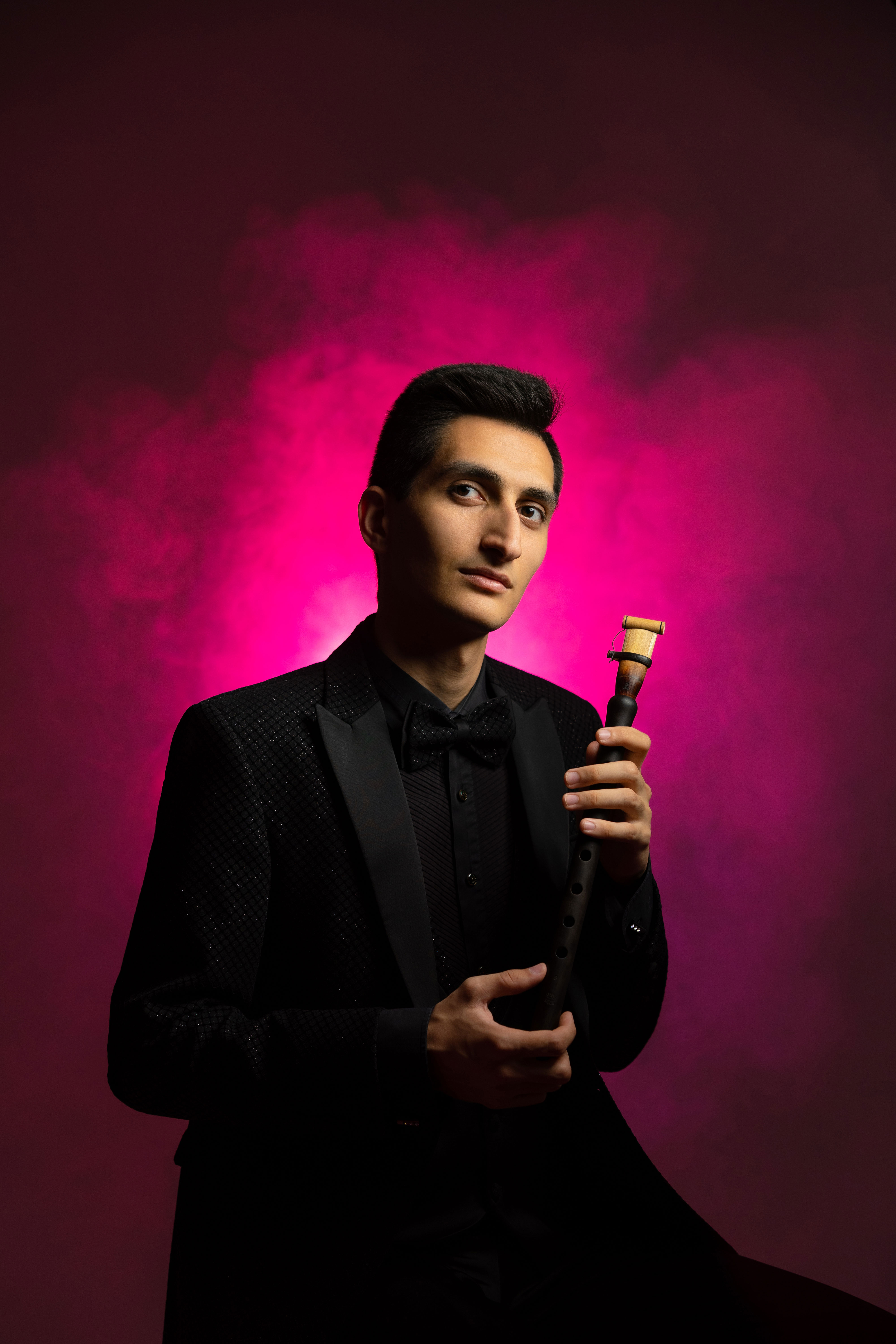 Erik Mirzoyan holding a duduk against a magenta-lit background