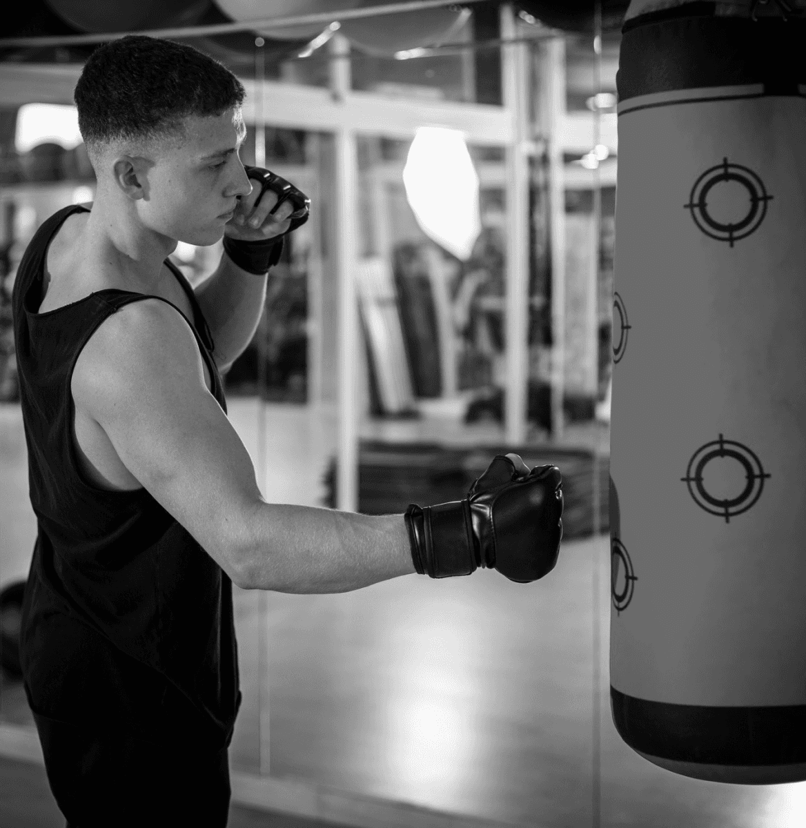 Fit man punching heavy bag during training