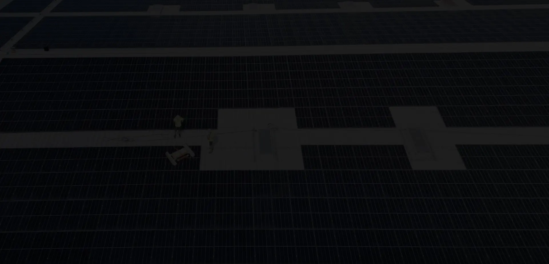 Techinicieni întreținere și curățare panouri solare folosind robot pe o hală