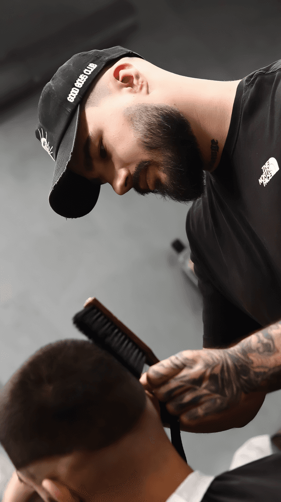 A barber skillfully styling a client's hair with a straightener in a modern barbershop setting.