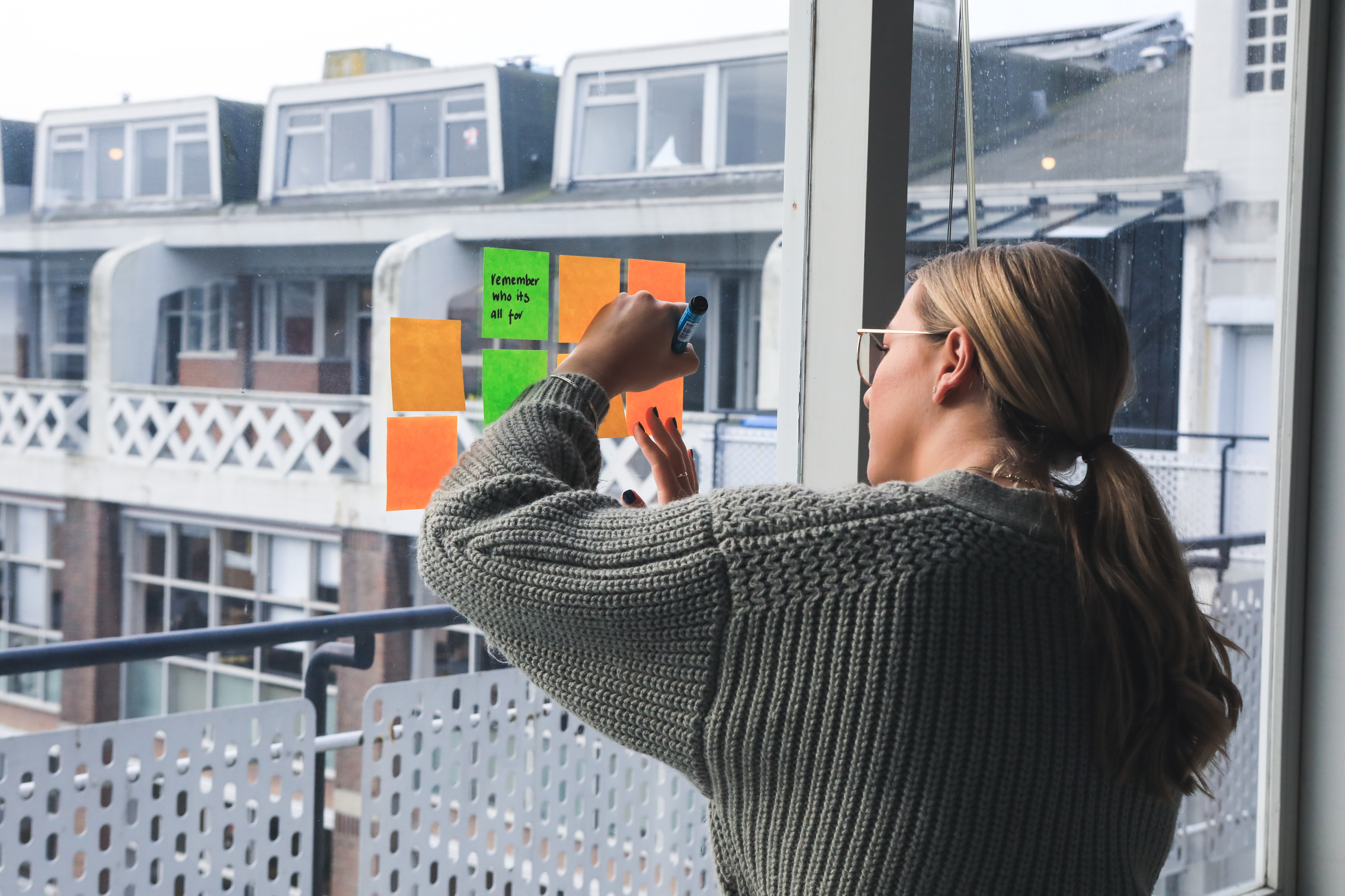 woman adding brainstorming ideas on window - how to write a song for beginners