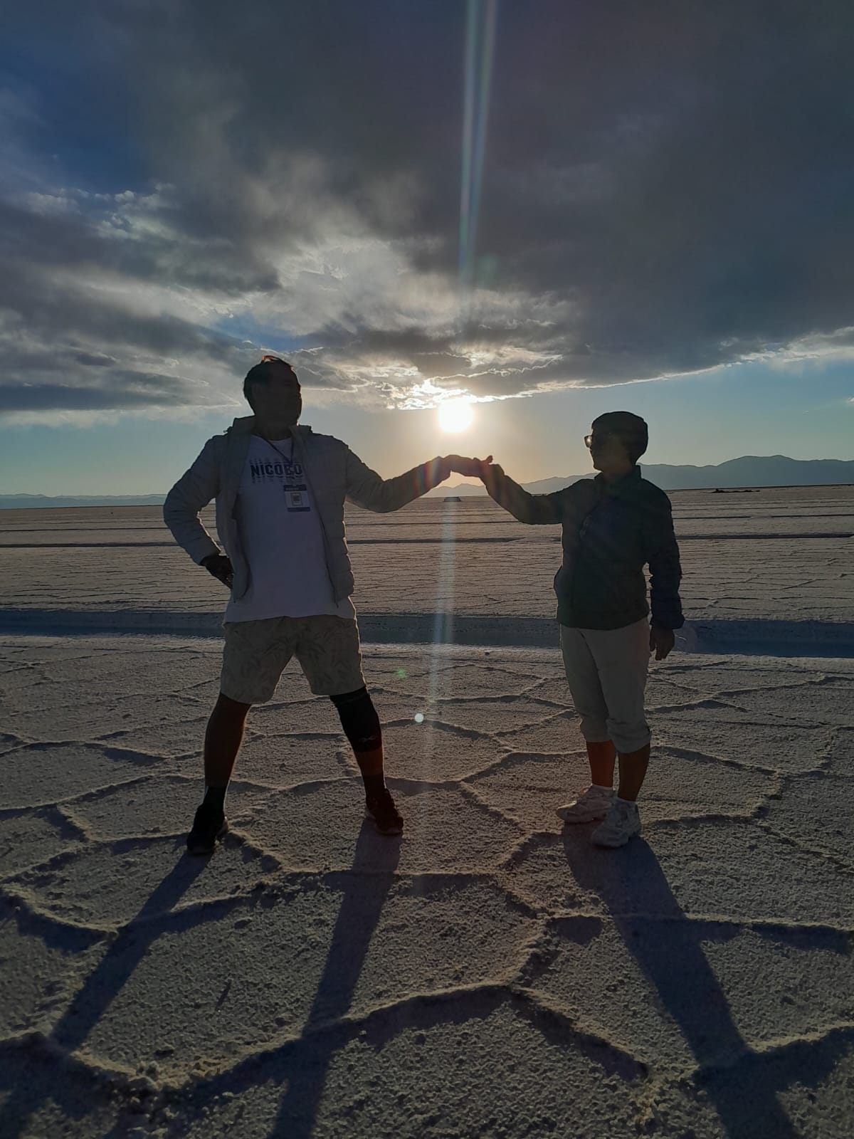 Mujer sentada sobre un tronco frente a una cascada doble en un bosque frondoso de Argentina.
