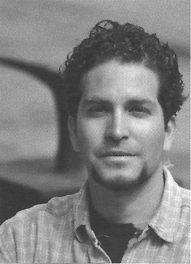Black and white portrait of a man with curly hair in a button-down shirt.