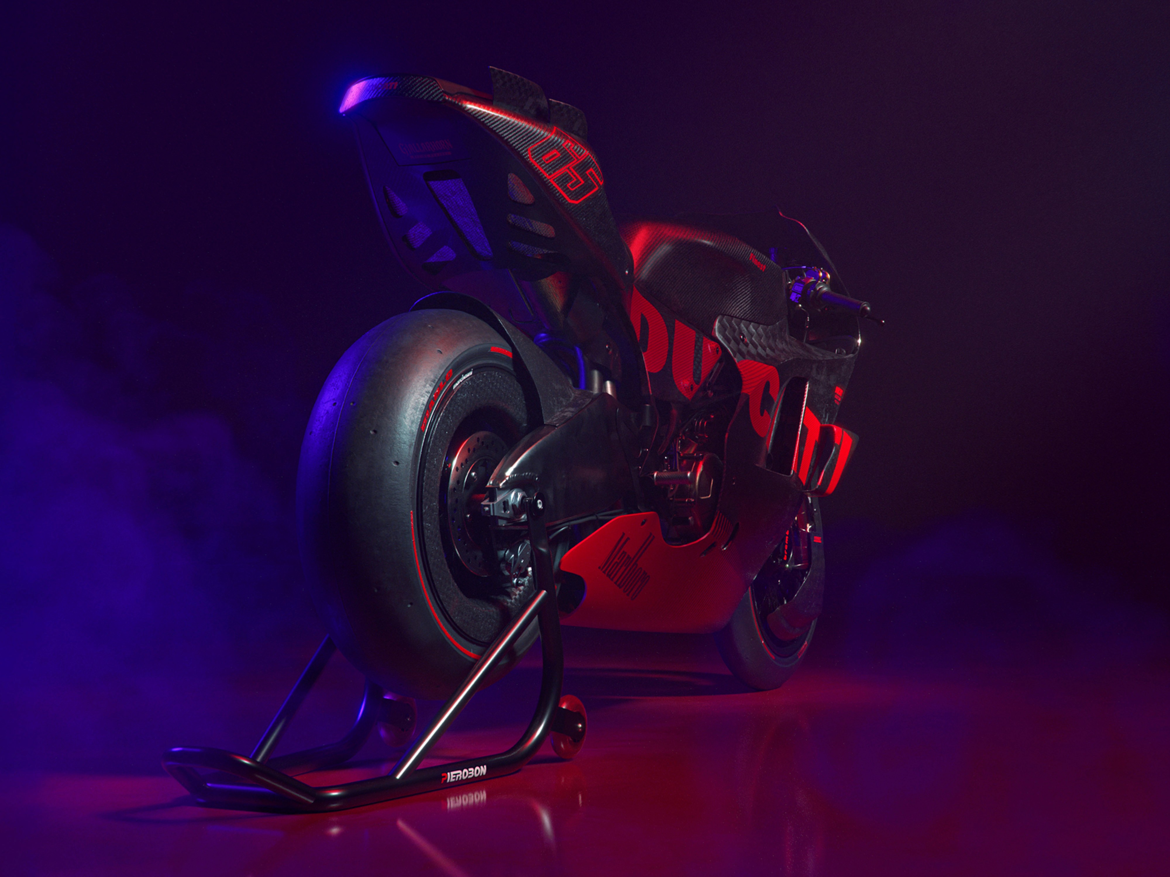 Visualizzazione vista tre quarti posteriore di moto da corsa Ducati nera con livrea rossa in ambiente scuro e cinematico.