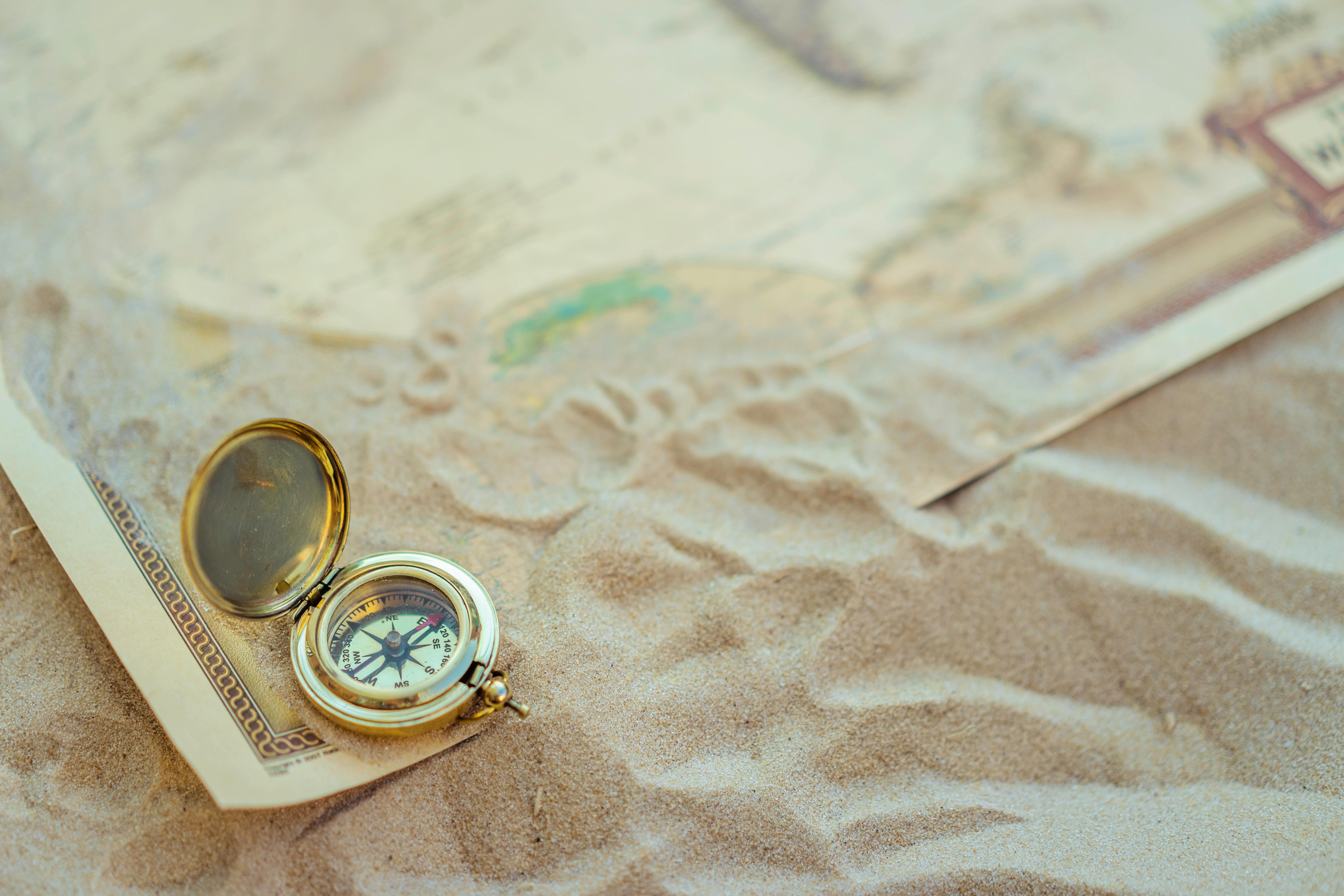 A map and compass spread out on sandy ground to demonstrate an adventure with a guide