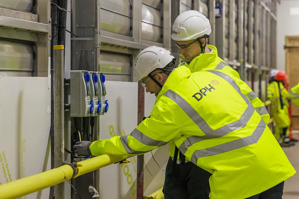 Entrance of a modern glass building with illuminated facade and reflections
