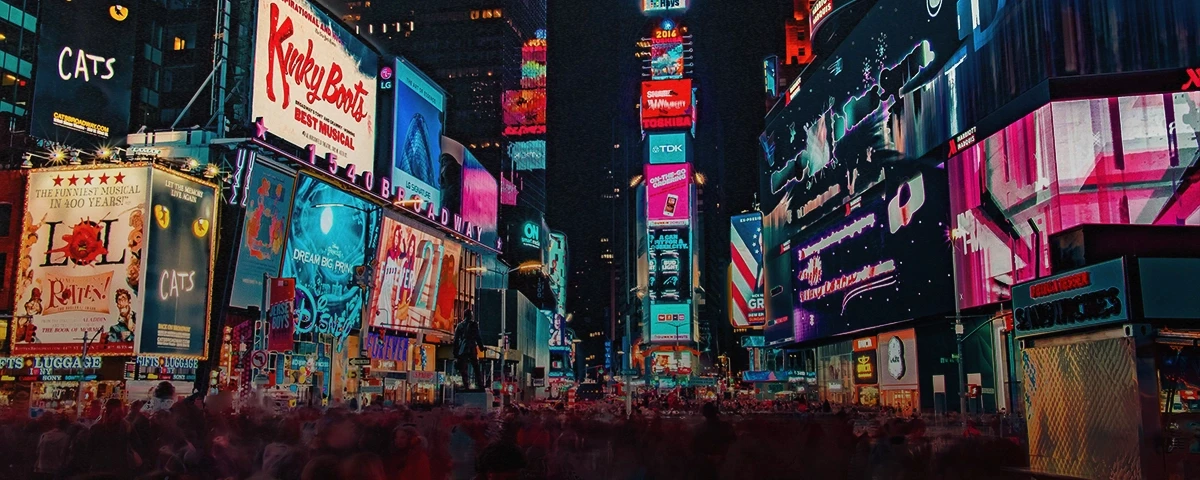 A photograph shot at night of the neon signs and lights of Times Square in New York city