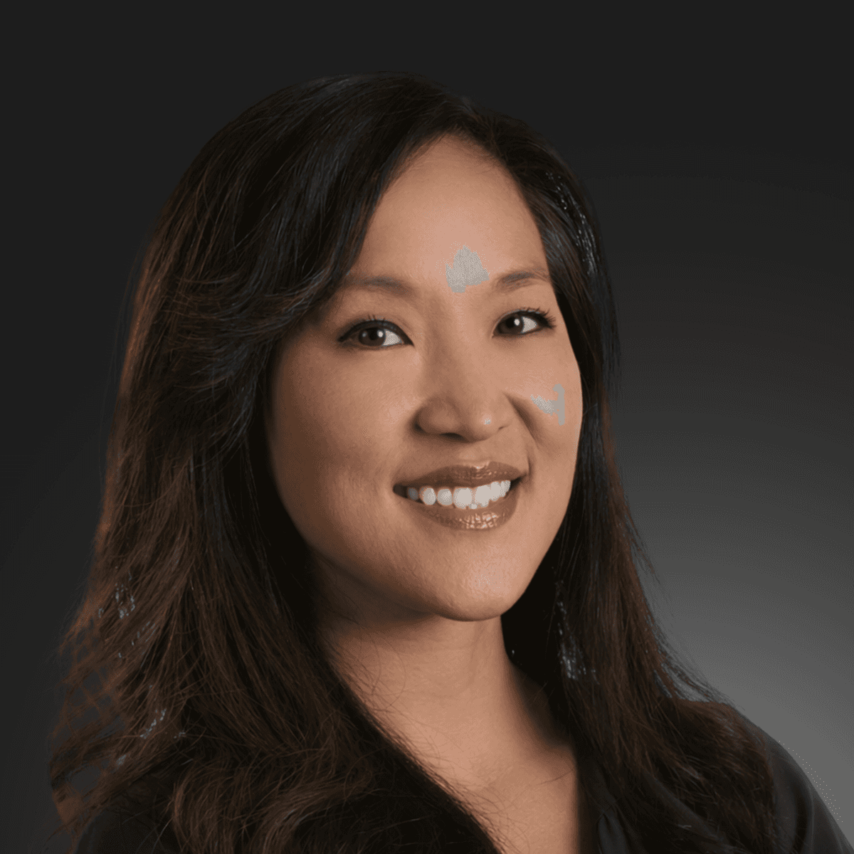 A man with glasses and a beard is looking directly at the camera, seated in a cozy, dimly lit café.