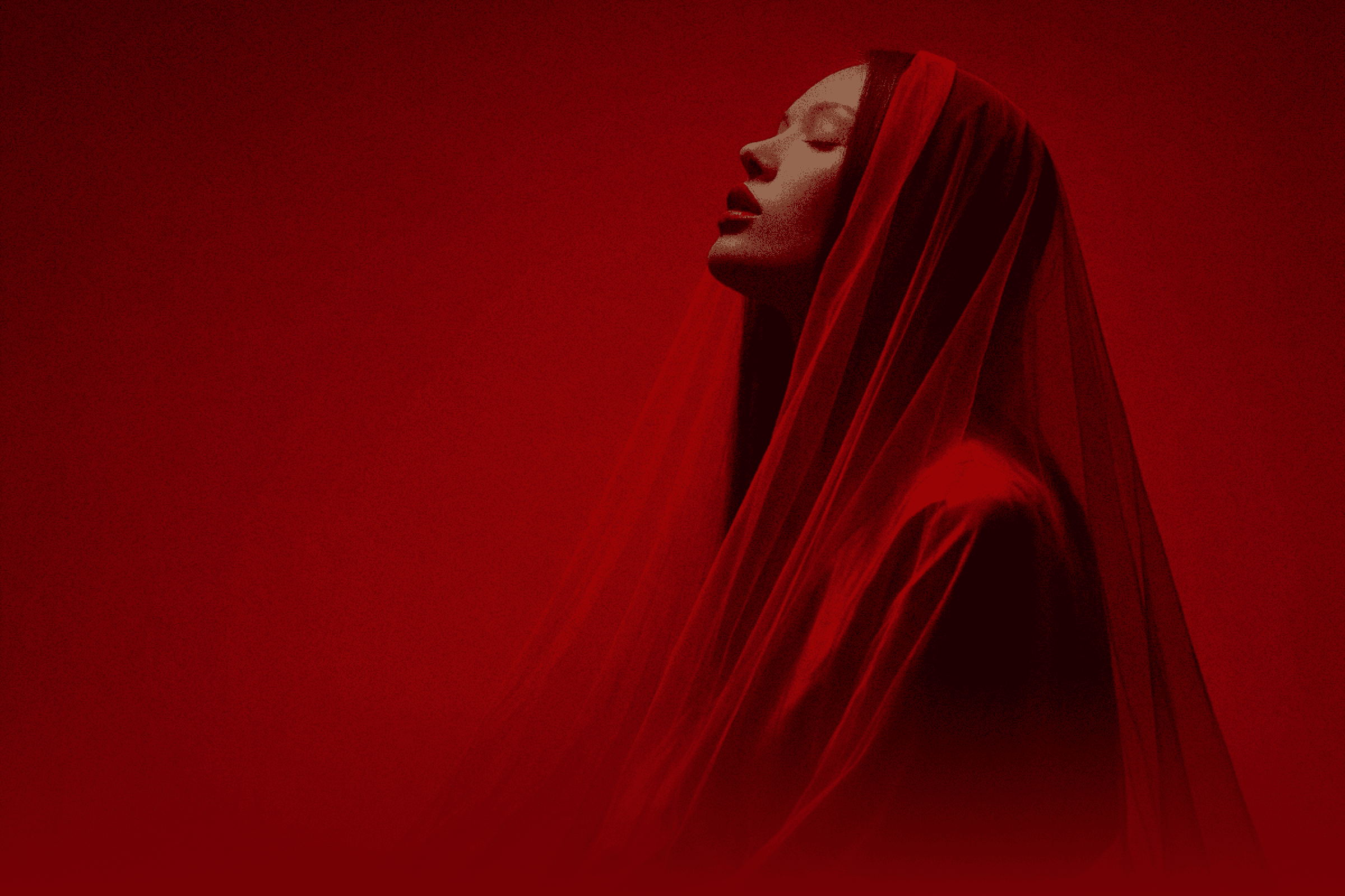 A woman wearing a red veil looks up, her face reflecting curiosity and contemplation.
