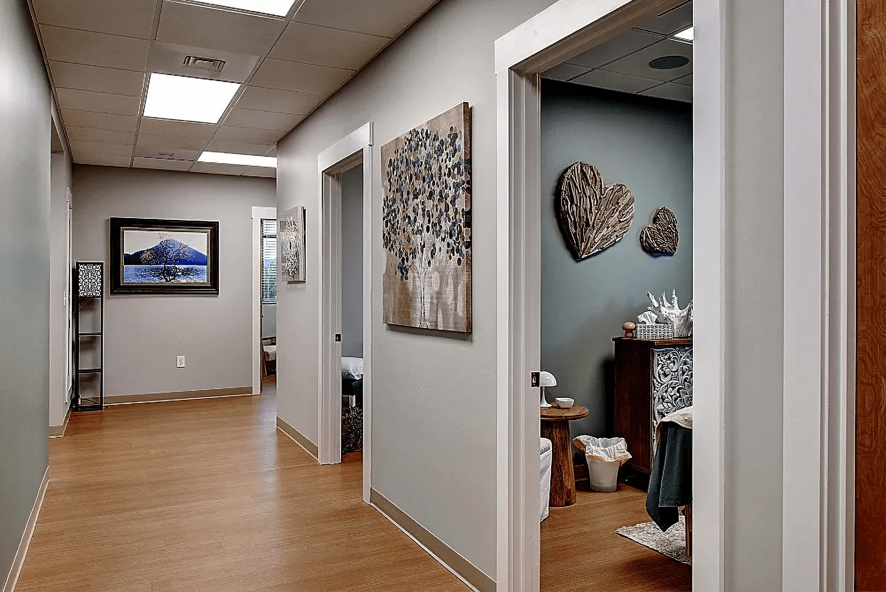 A well-lit hallway with several doors, leading to rooms with modern decor and light wood flooring.