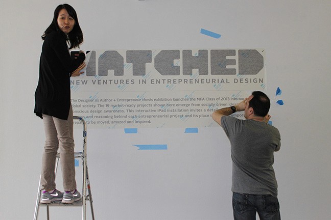 A photo of two persons imprinting on a wall the text Hatched along with other useful information.