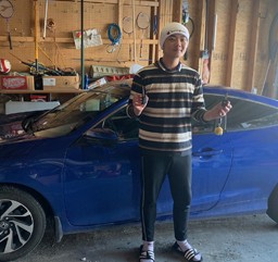 Happy customer holding new car keys maade by CarKeyAction beside his blue honda civic.