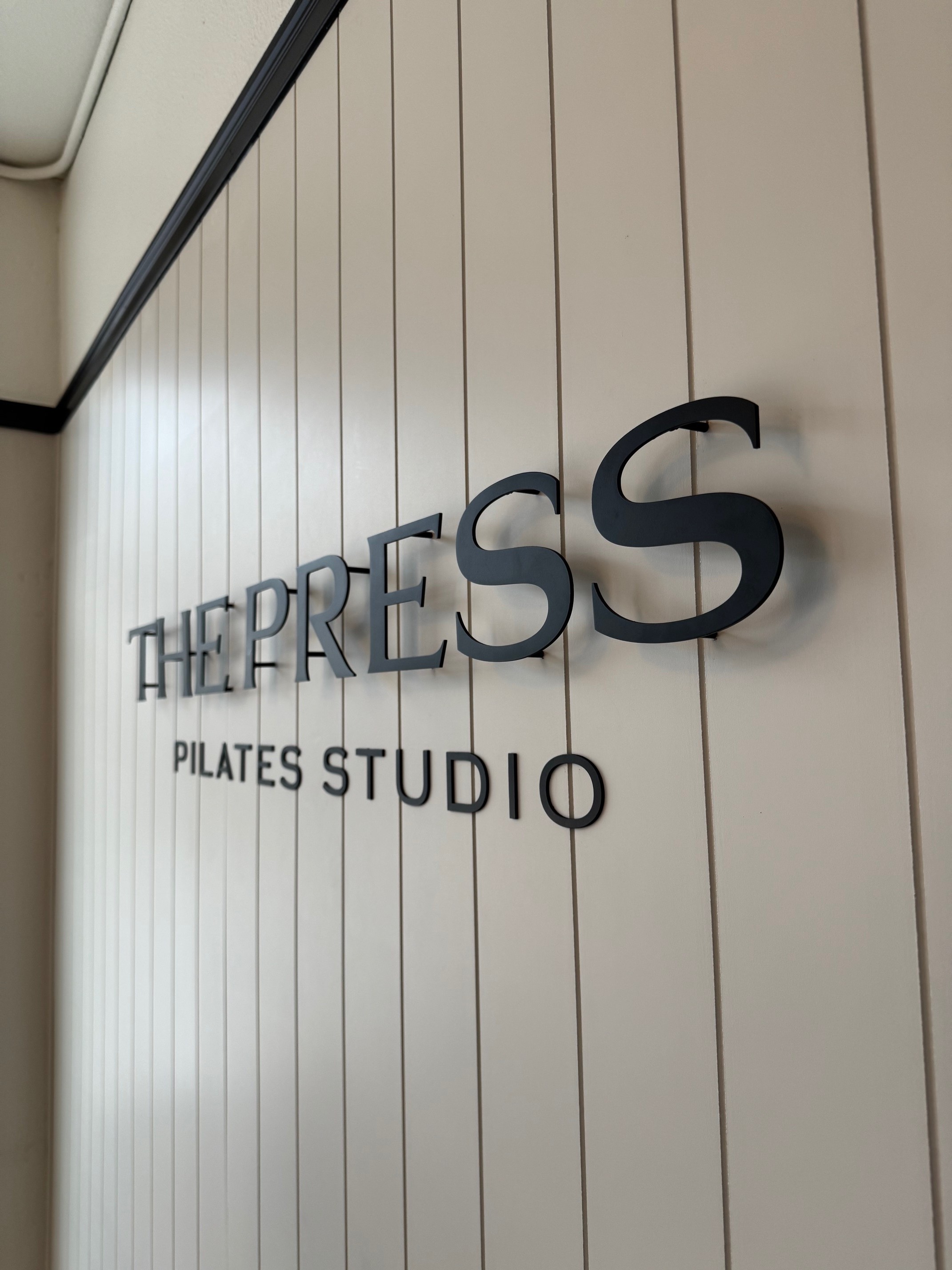 Person taking a big bite of a fried chicken burger with cheese, lettuce, tomato, and pickles, wearing a green striped shirt.