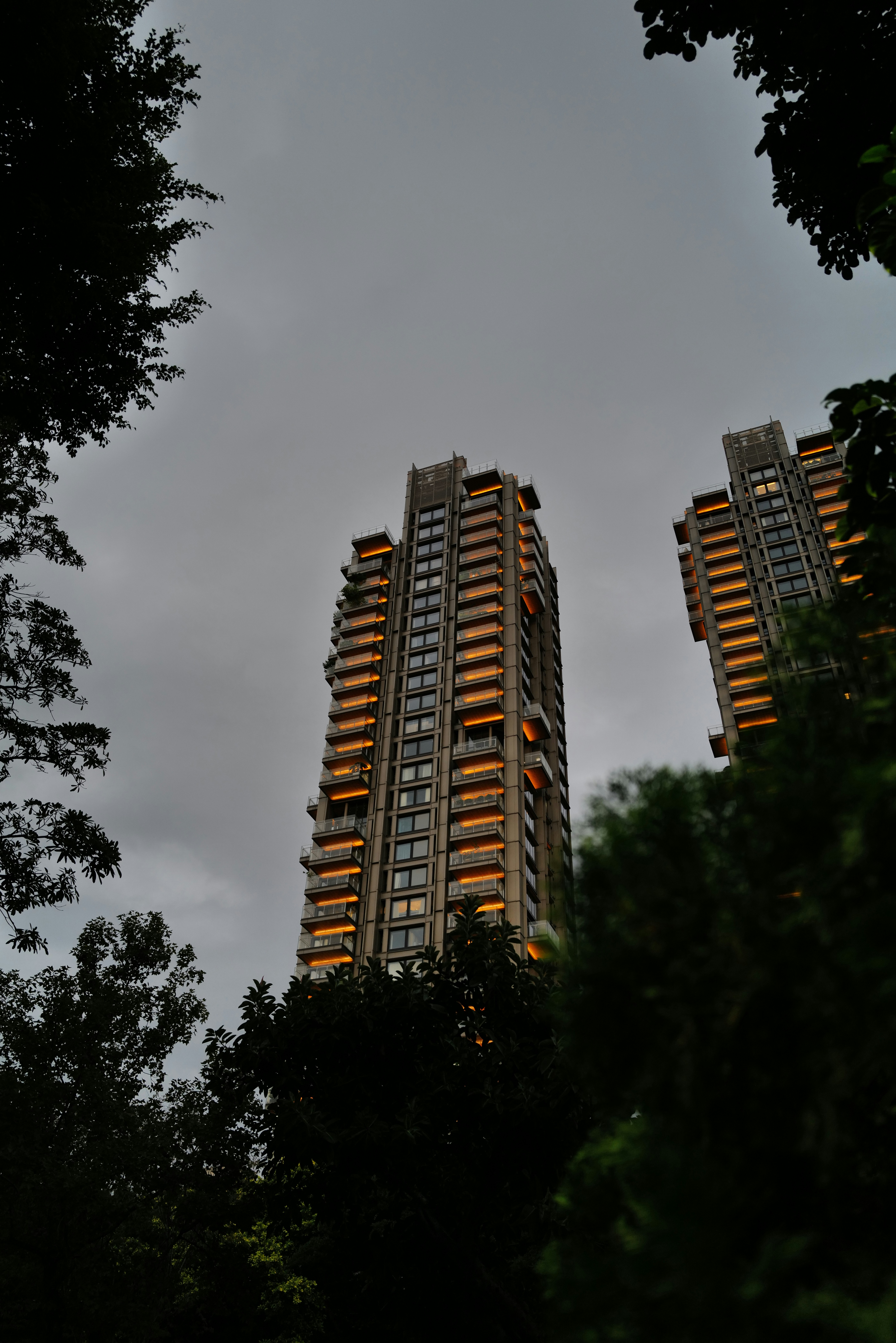 Two tall buildings with illuminated balconies at dusk