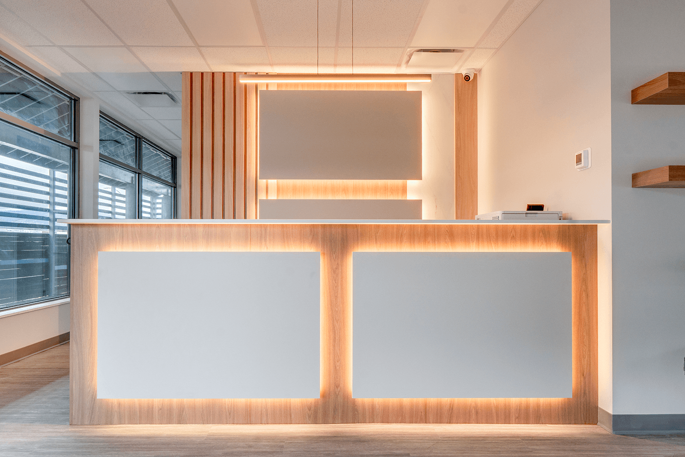 Front-facing view of the LED-lit reception desk showcasing warm wood details and minimalist design.