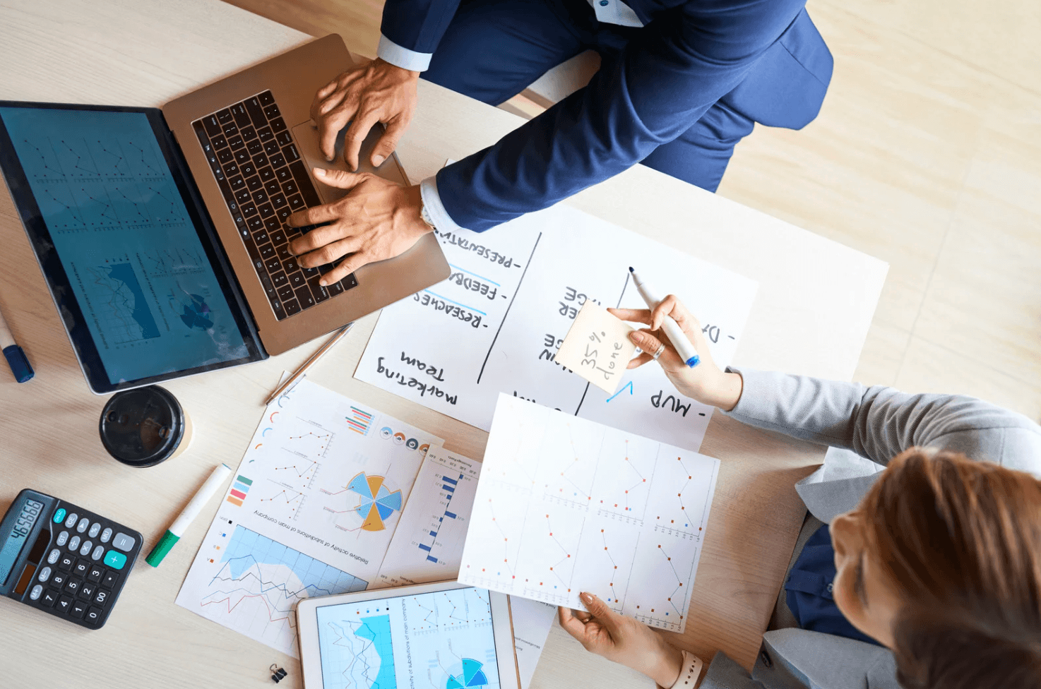 Two professionals reviewing charts and marketing data beside a laptop, illustrating how managing too many Amazon PPC campaigns can create complexity and inefficiency without automation to centralise control.