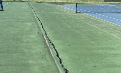 Tennis court crack showing surface damage and need for repair.
