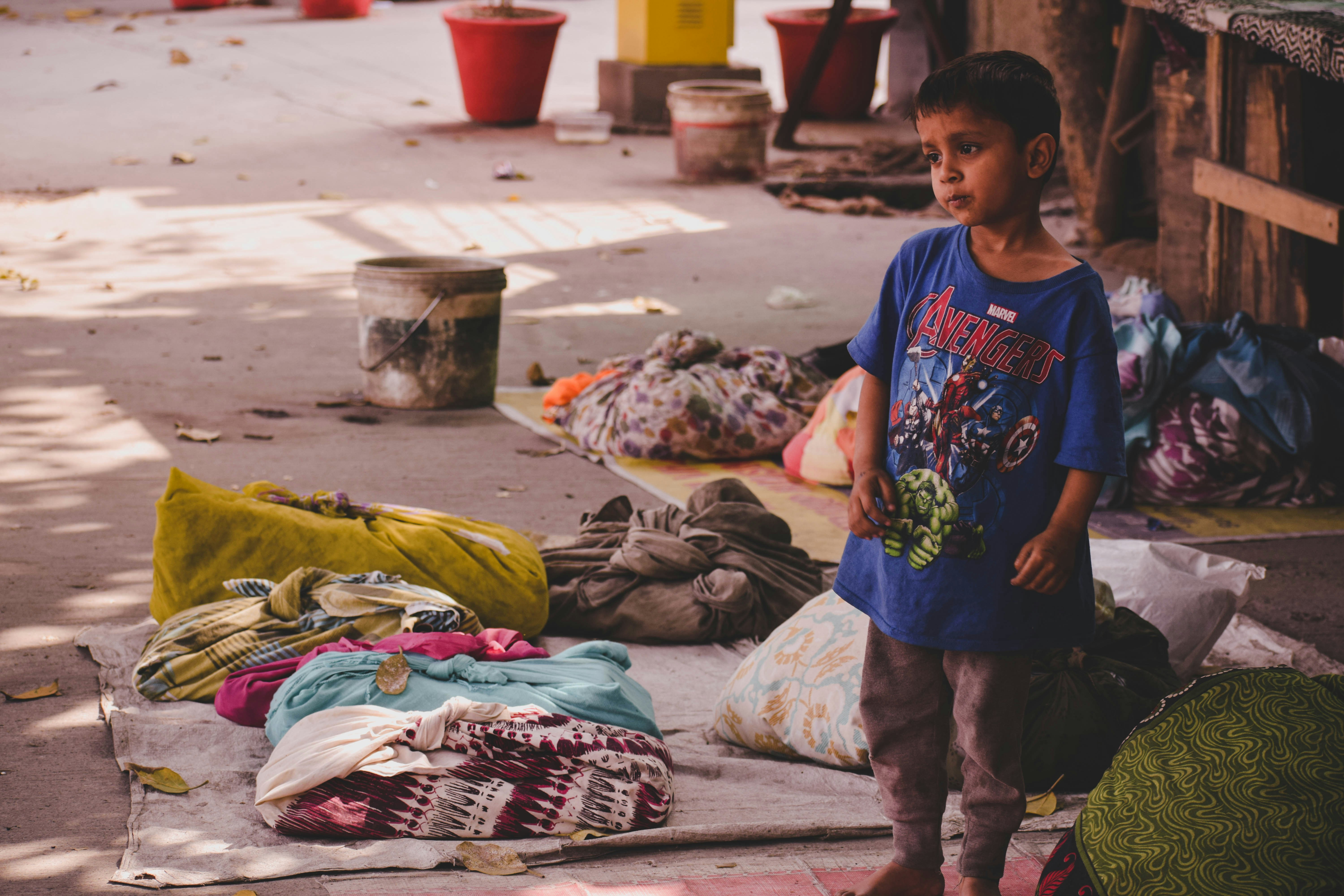 boy in blue crew neck t-shirt standing on red and white textile