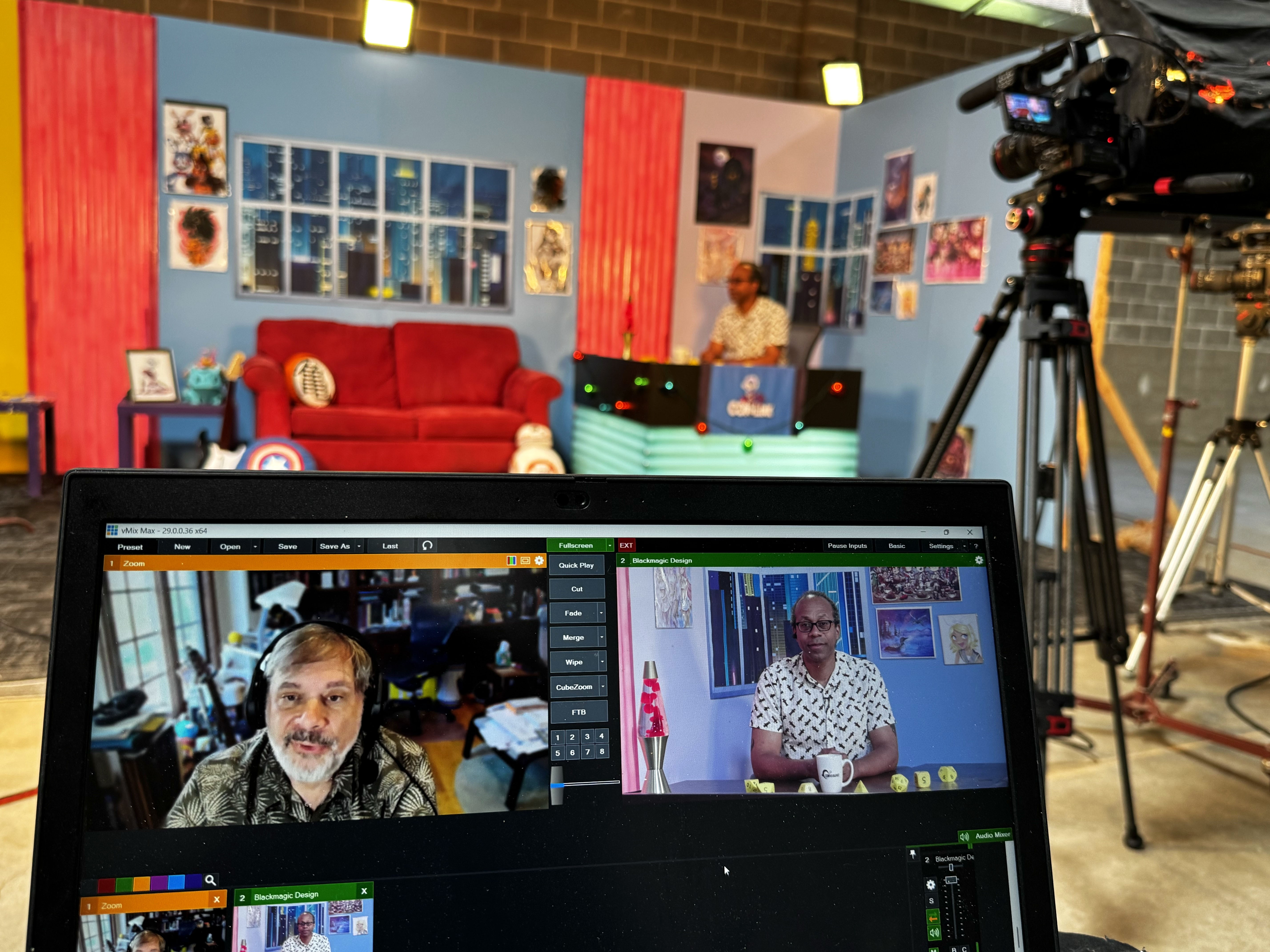 Behind-the-scenes view of a live video podcast set with a camera tripod and a monitoring laptop screen.