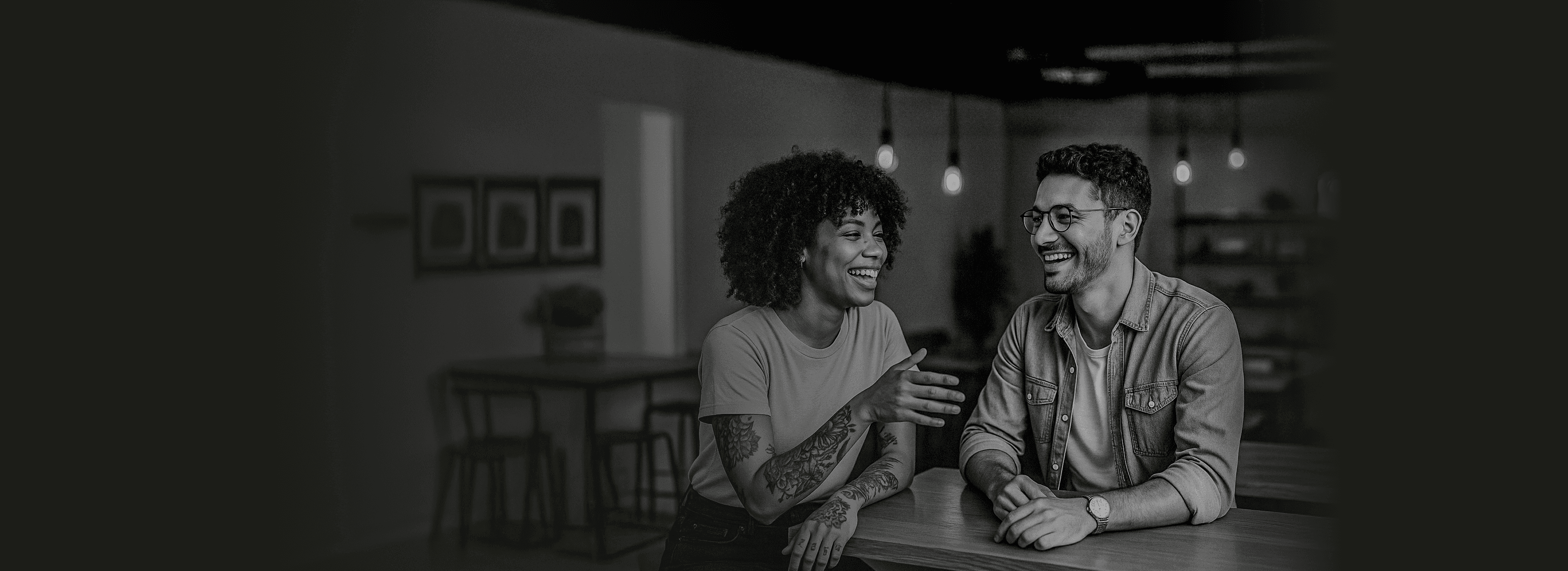 Casal de empreendedores da economia criativa em ambiente moderno e acolhedor, sorrindo em momento de colaboração