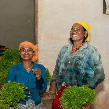 Two smiling woman holding crops
