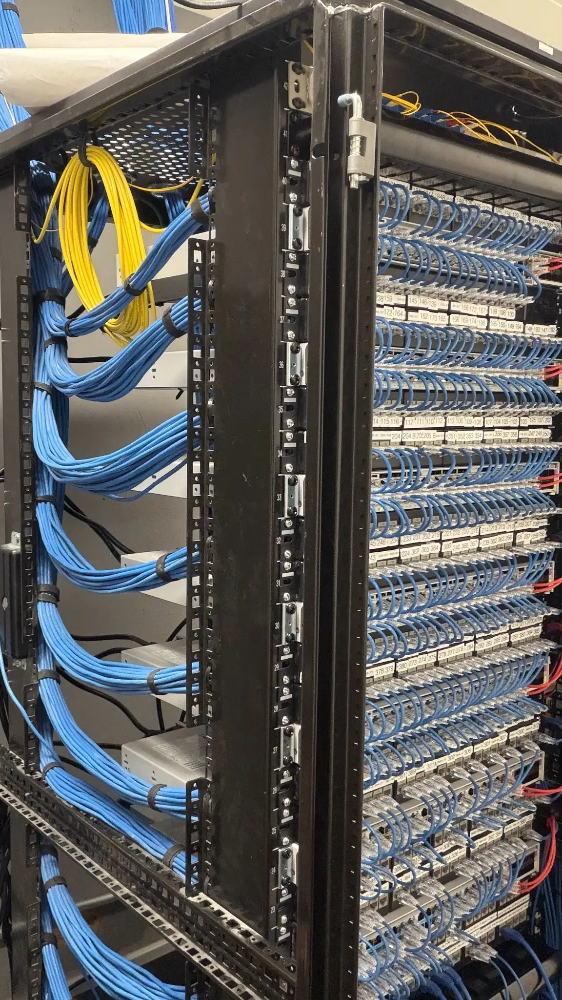 Organized server rack with structured network cabling, featuring labeled patch panels, blue Ethernet cables, and clean cable management in a data center environment